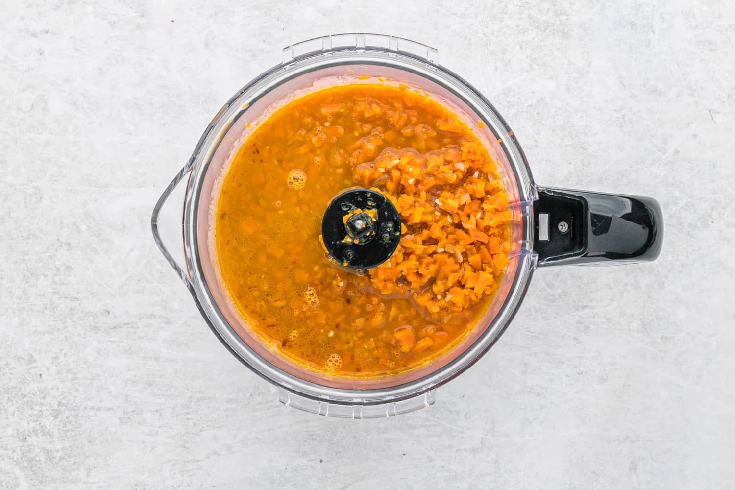 Carrots in a food processor, partially blended.