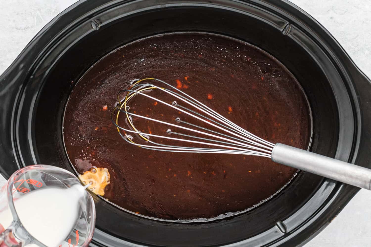 Sauce being thickened with cornstarch.