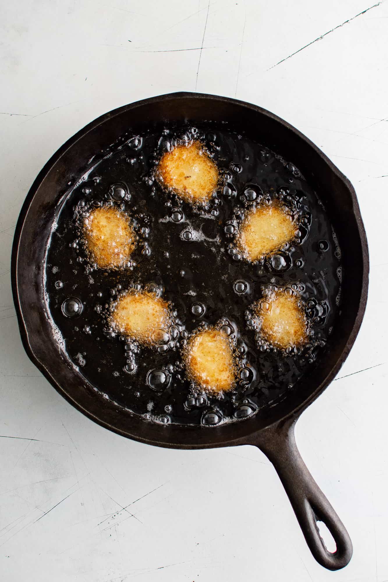 Goat cheese being fried in a cast iron skillet.