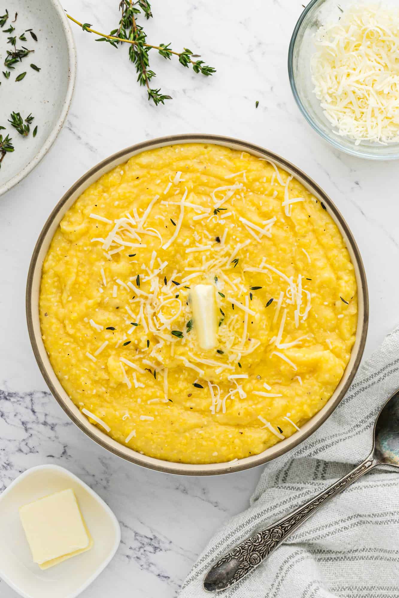 Instant pot polenta garnished with butter and fresh thyme.