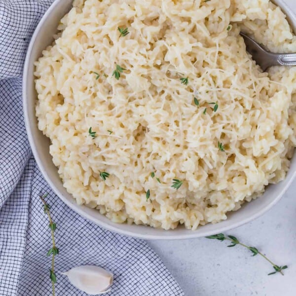 Bowl of instant pot risotto topped with parmesan cheese and fresh thyme.