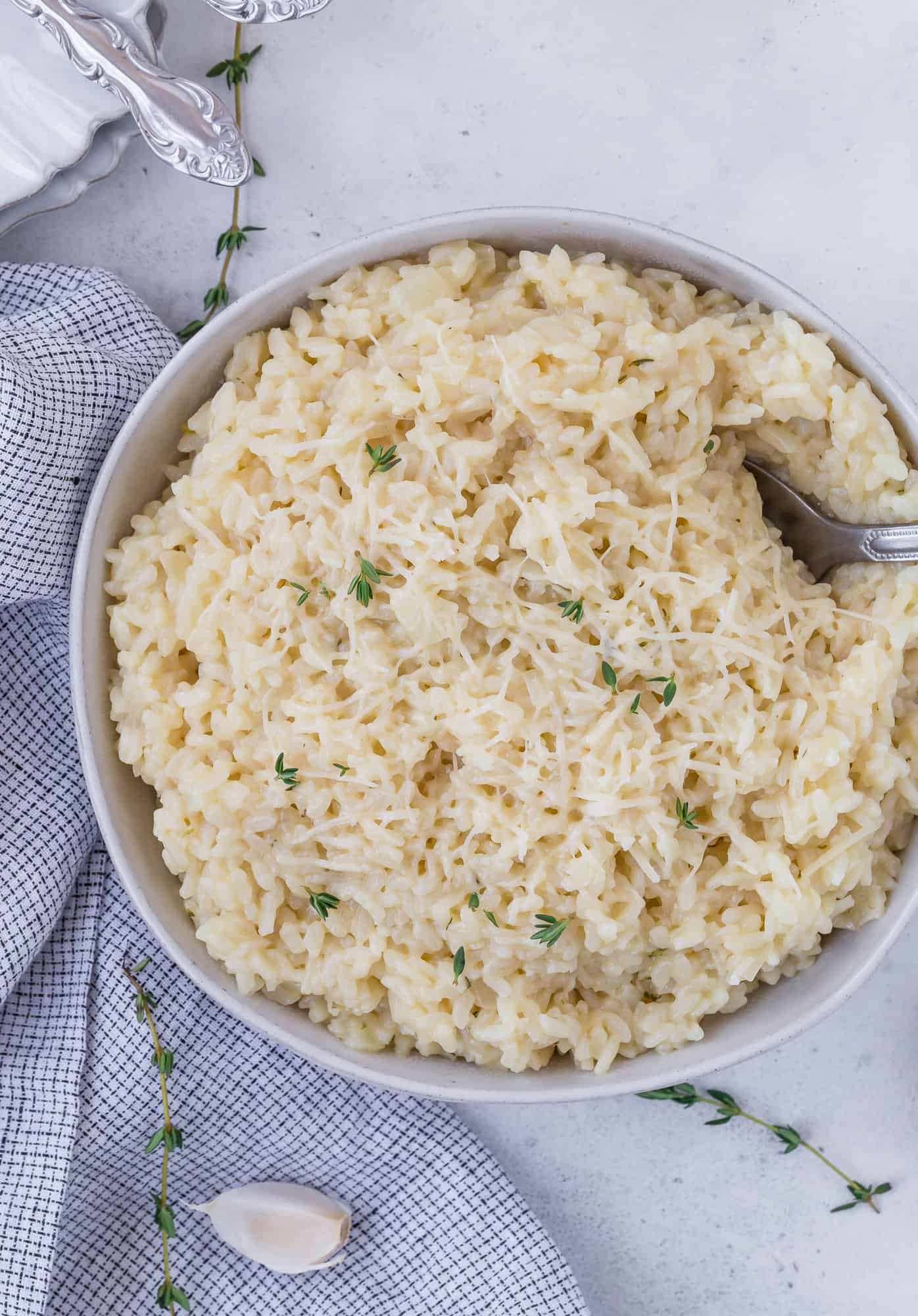 Bowl of instant pot risotto topped with parmesan cheese and fresh thyme.