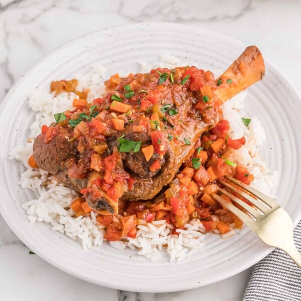 Braised lamb shank served on a white plate.