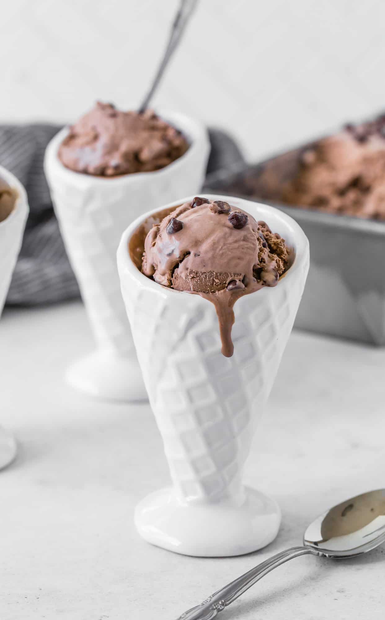Chocolate ice cream dripping down a white ceramic cone.