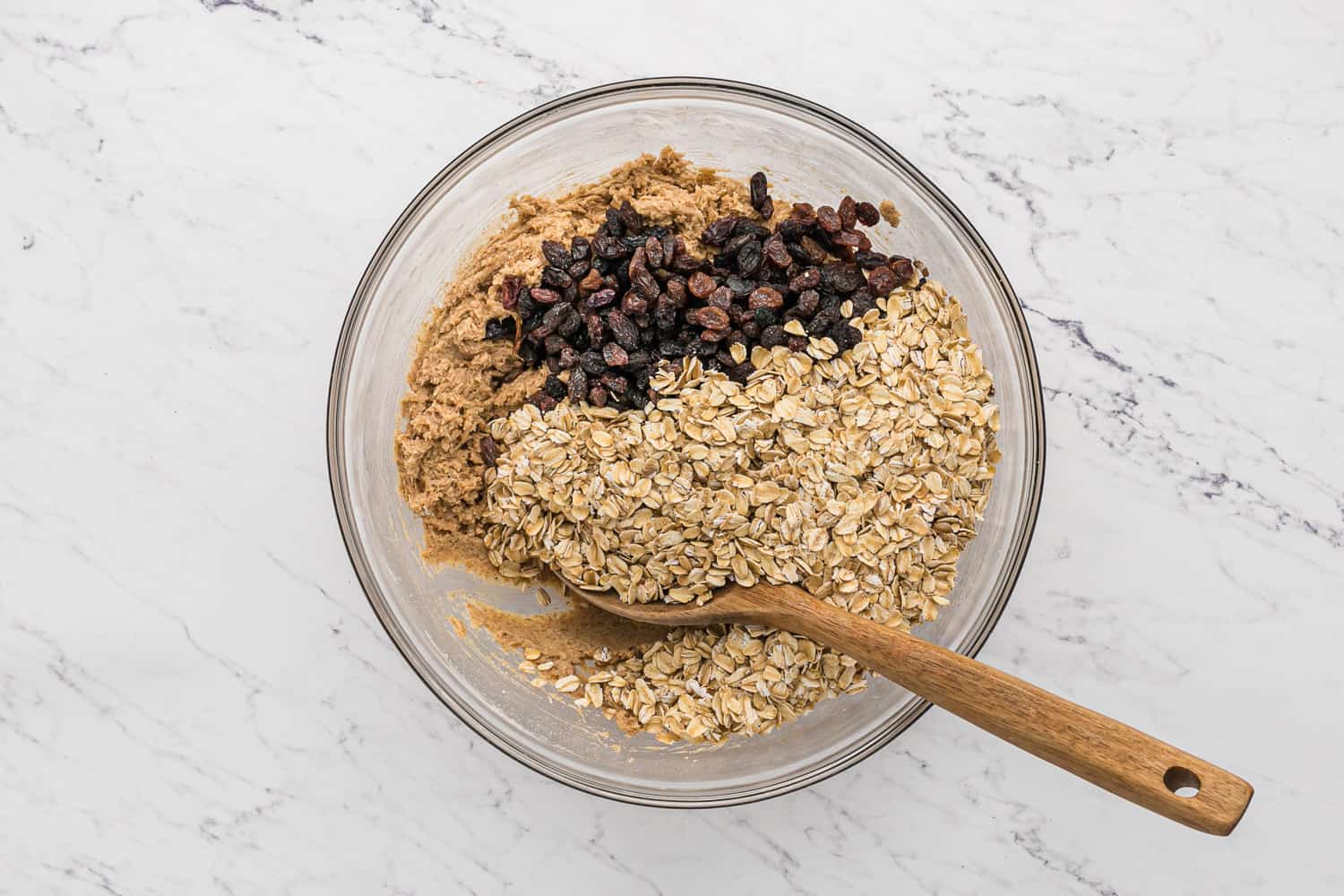 Oats and raisins being added to cookie dough.