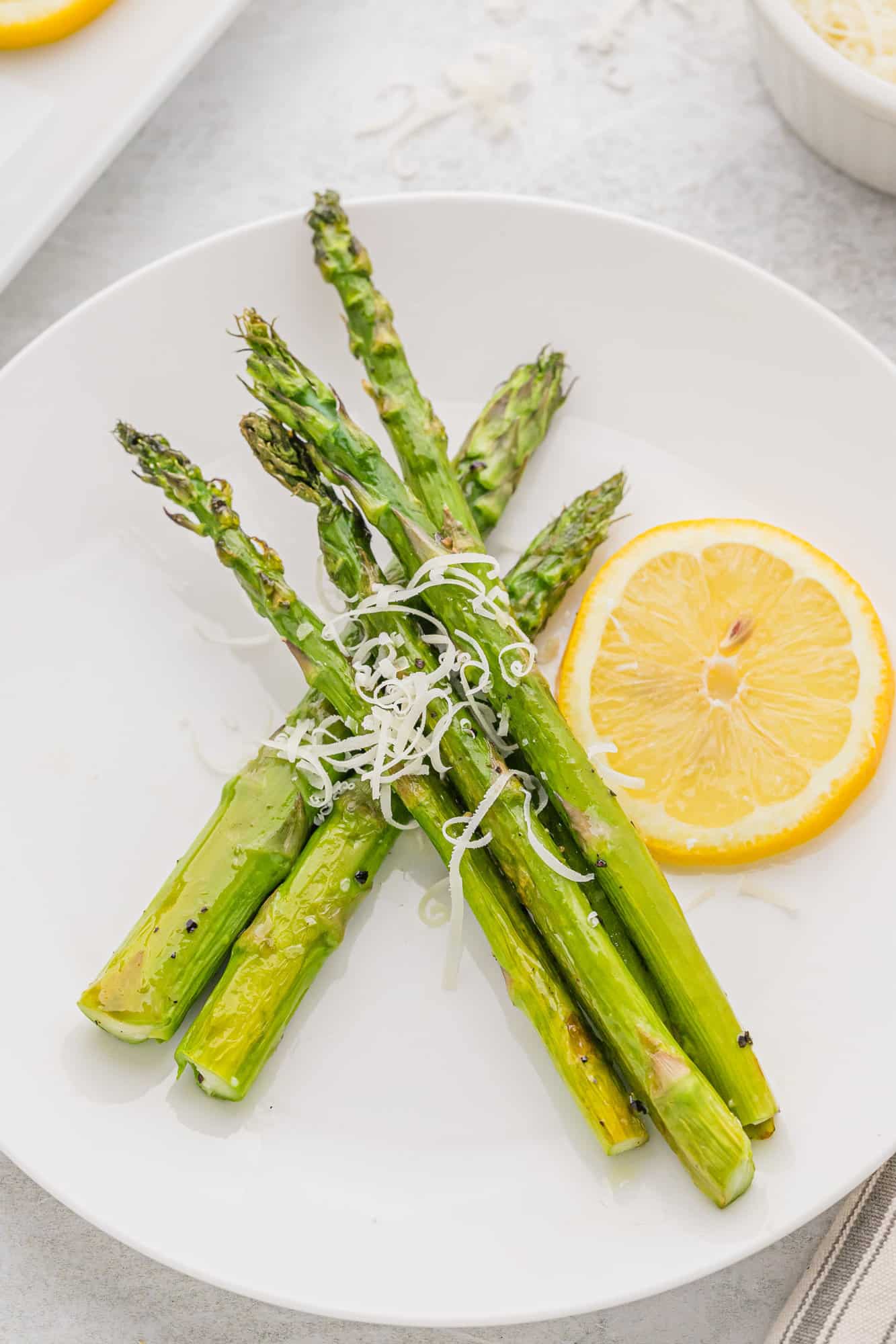Asparagus on a dinner plate with a lemon wheel.