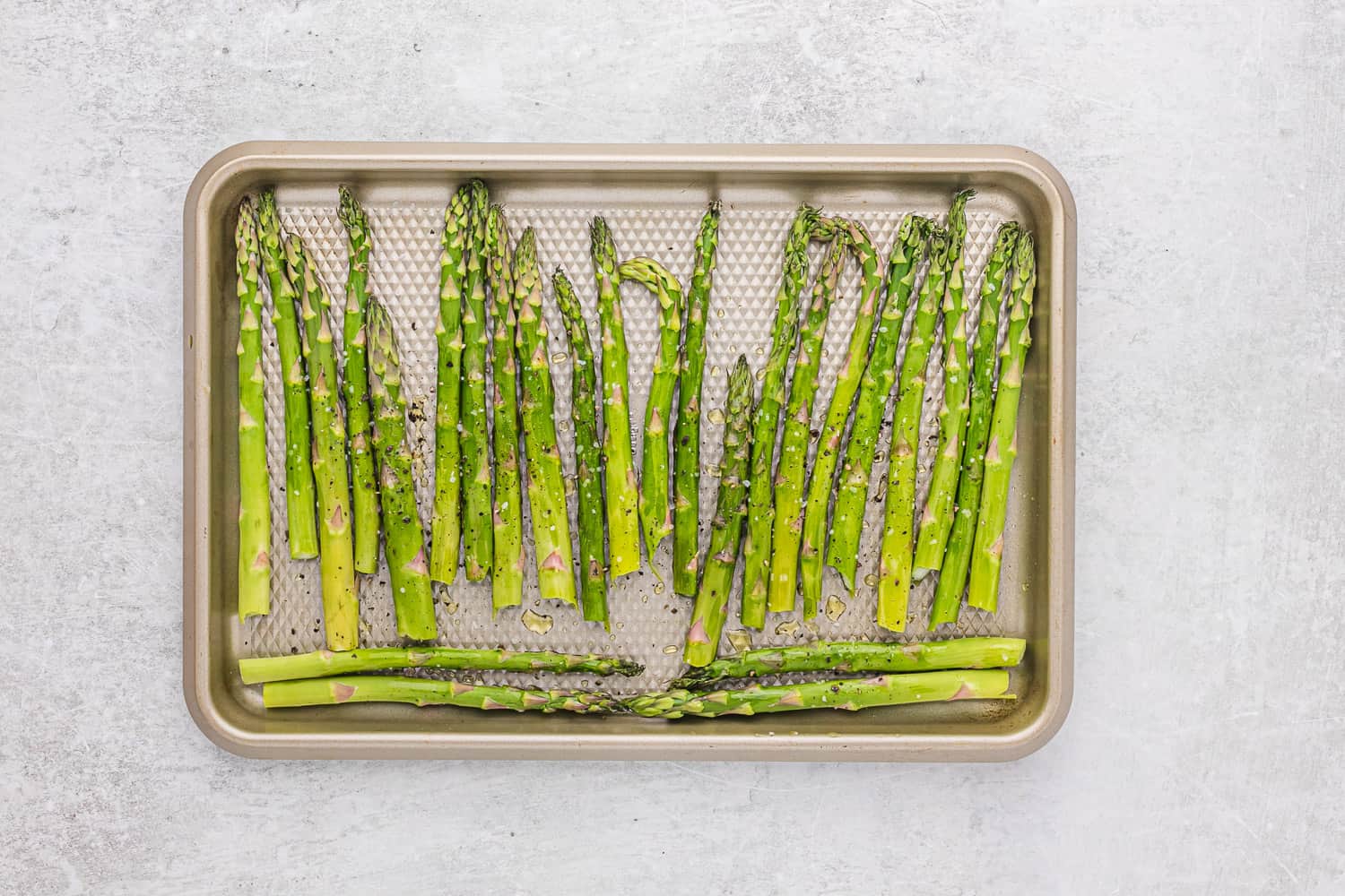 Unroasted asparagus on a sheet pan.