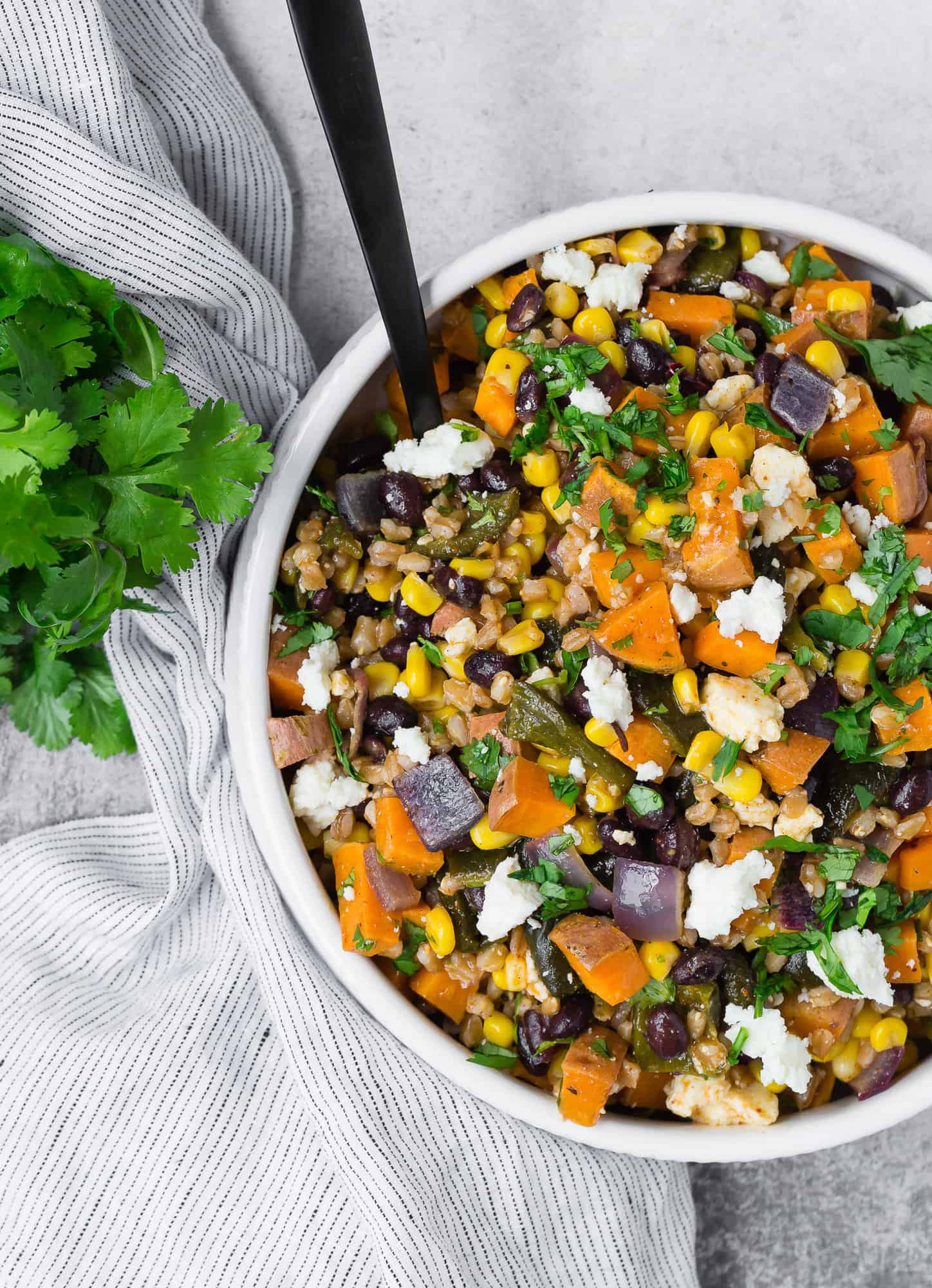 Farro salad with a black spoon. 