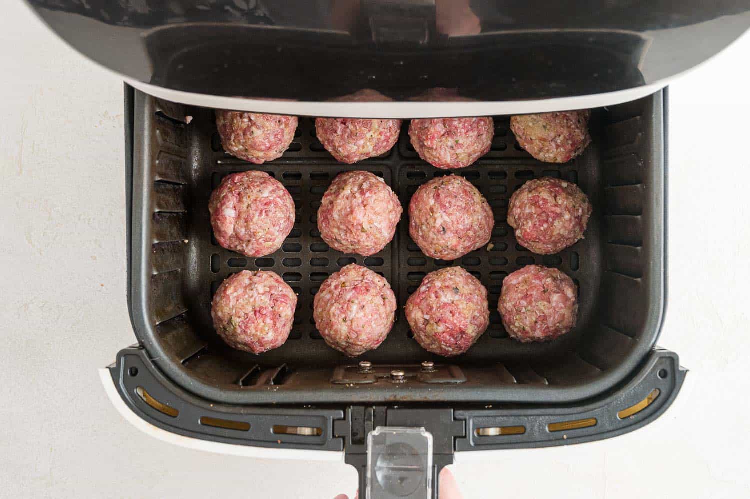 Uncooked meatballs in the air fryer.