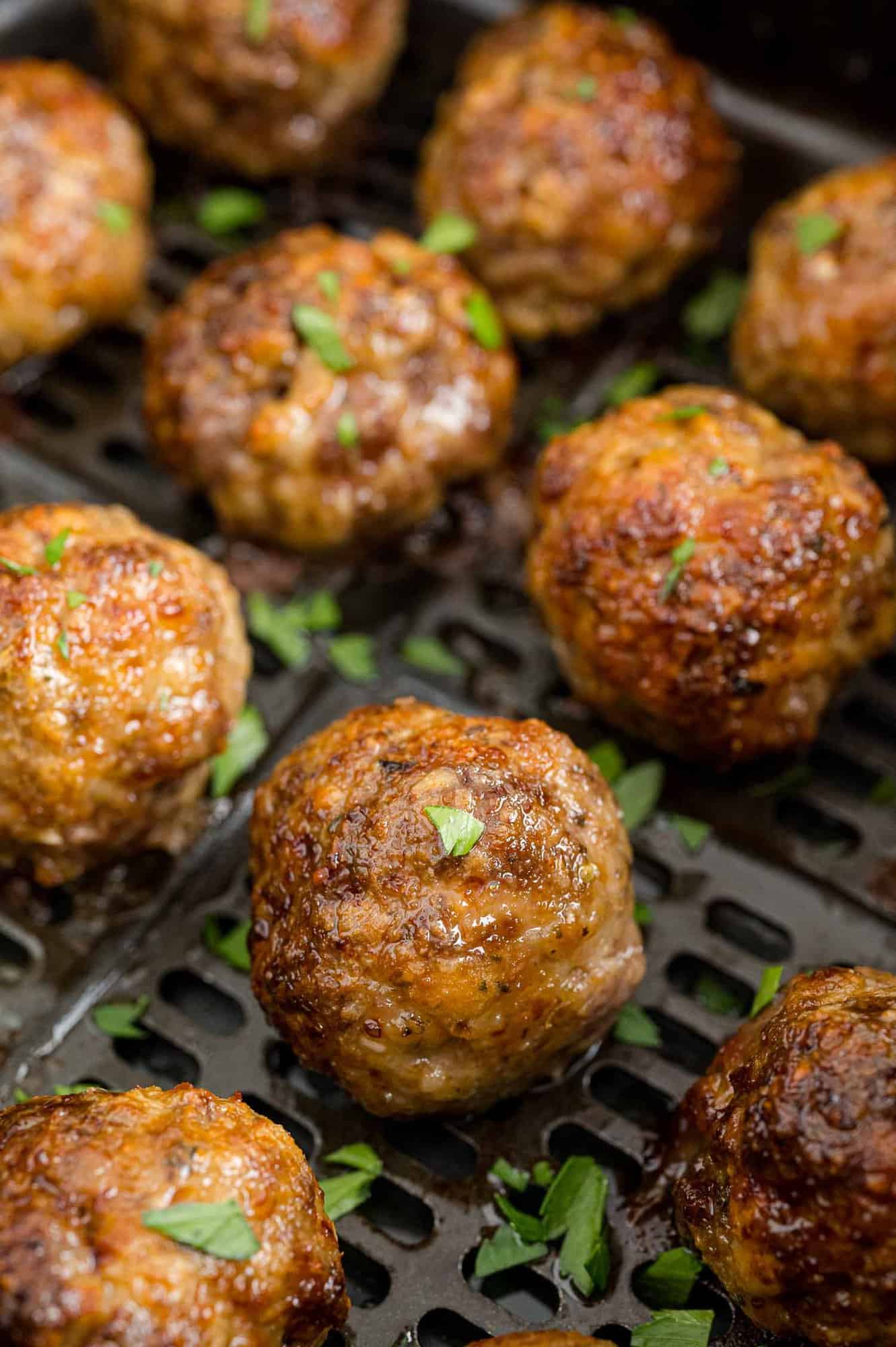 Meatballs in an air fryer basket.