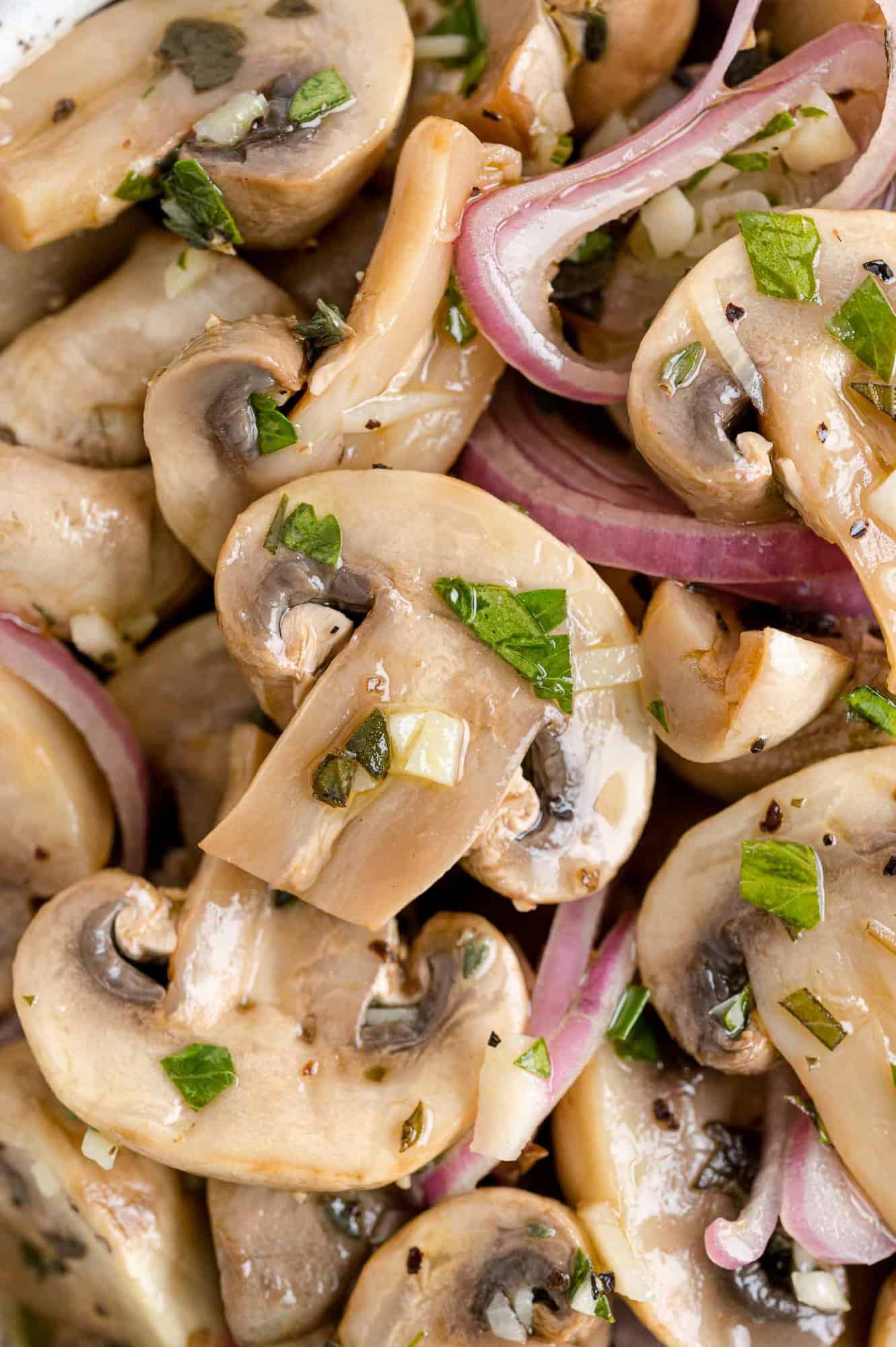 Close up of marinated mushrooms with herbs.