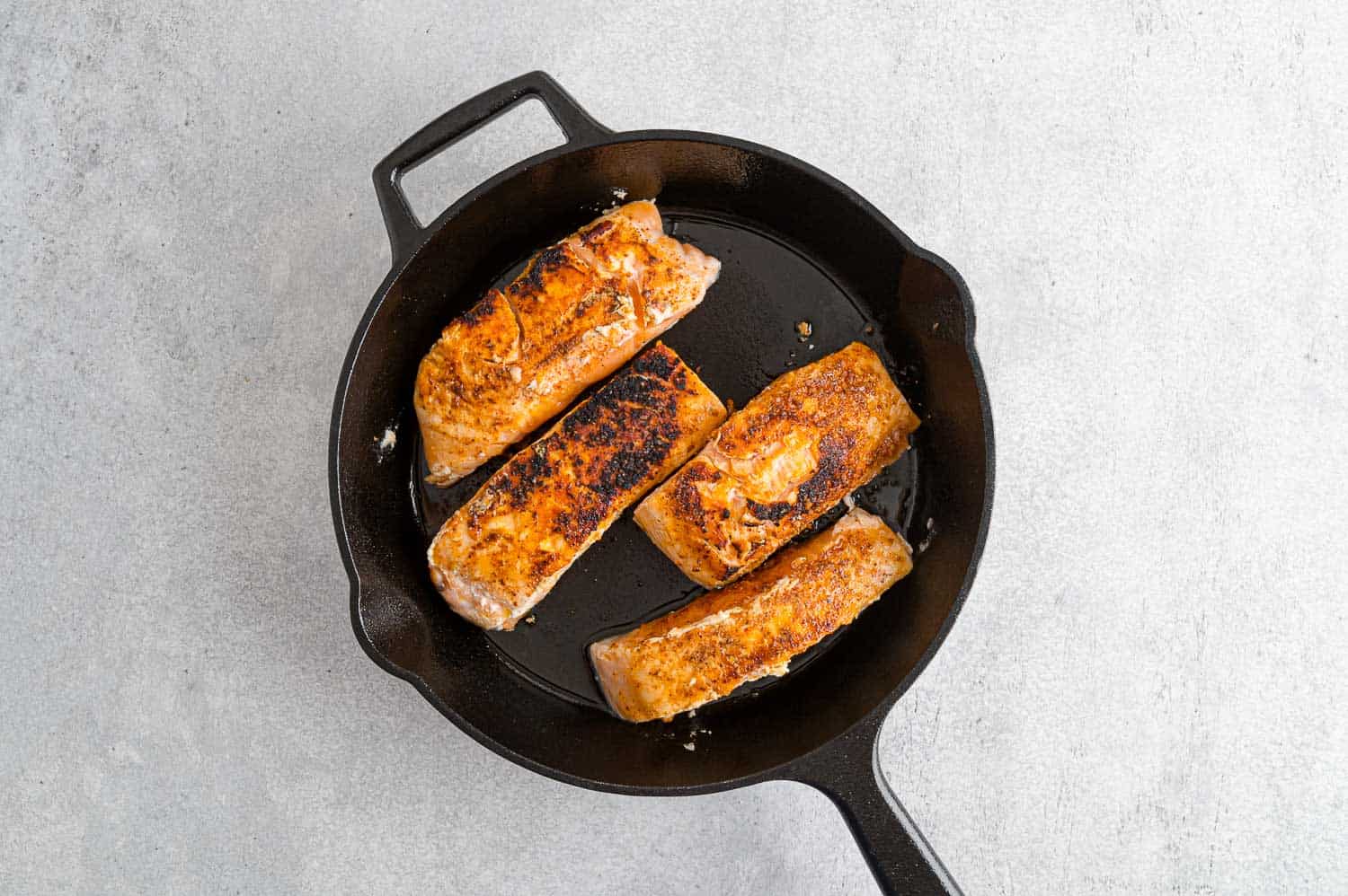 Seared salmon filets in skillet.