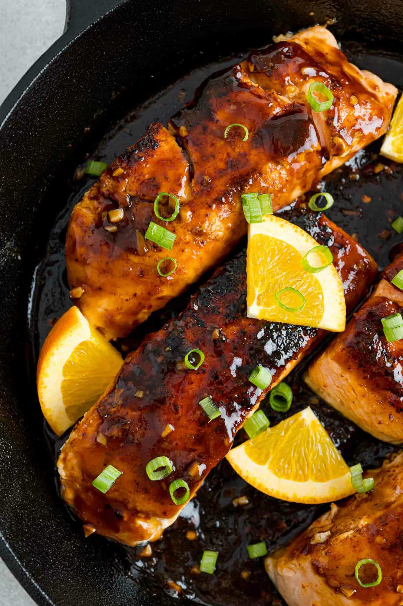 Orange glazed salmon in a cast iron pan.