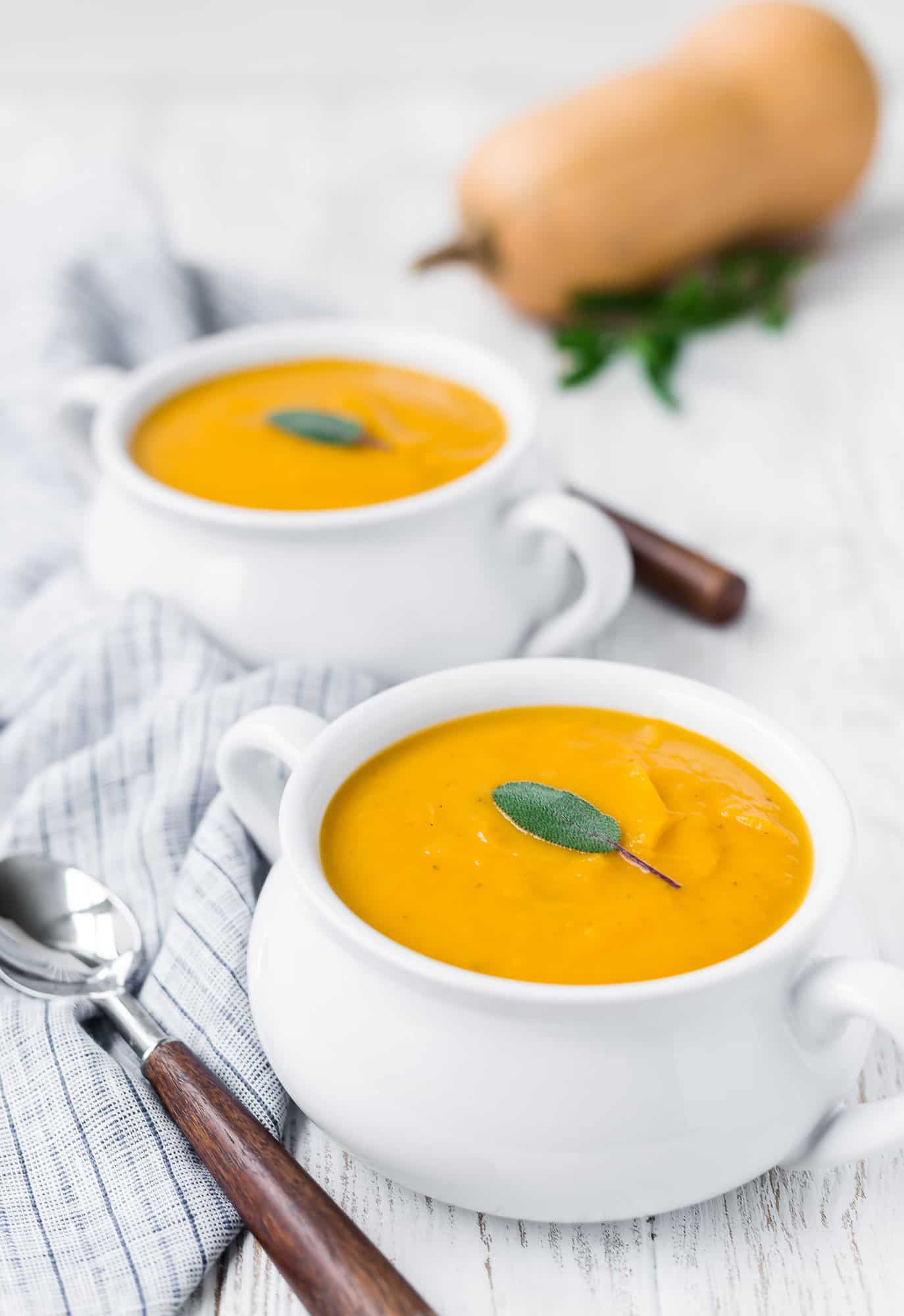 Two bowls of butternut squash soup with sage.