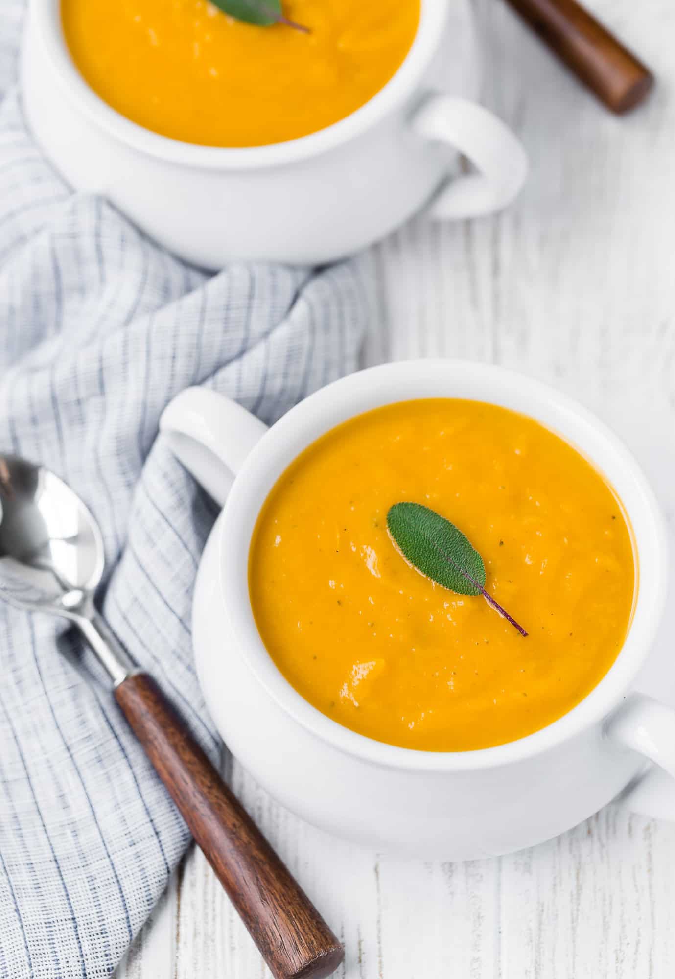 Bright orange squash soup with sage leaf.