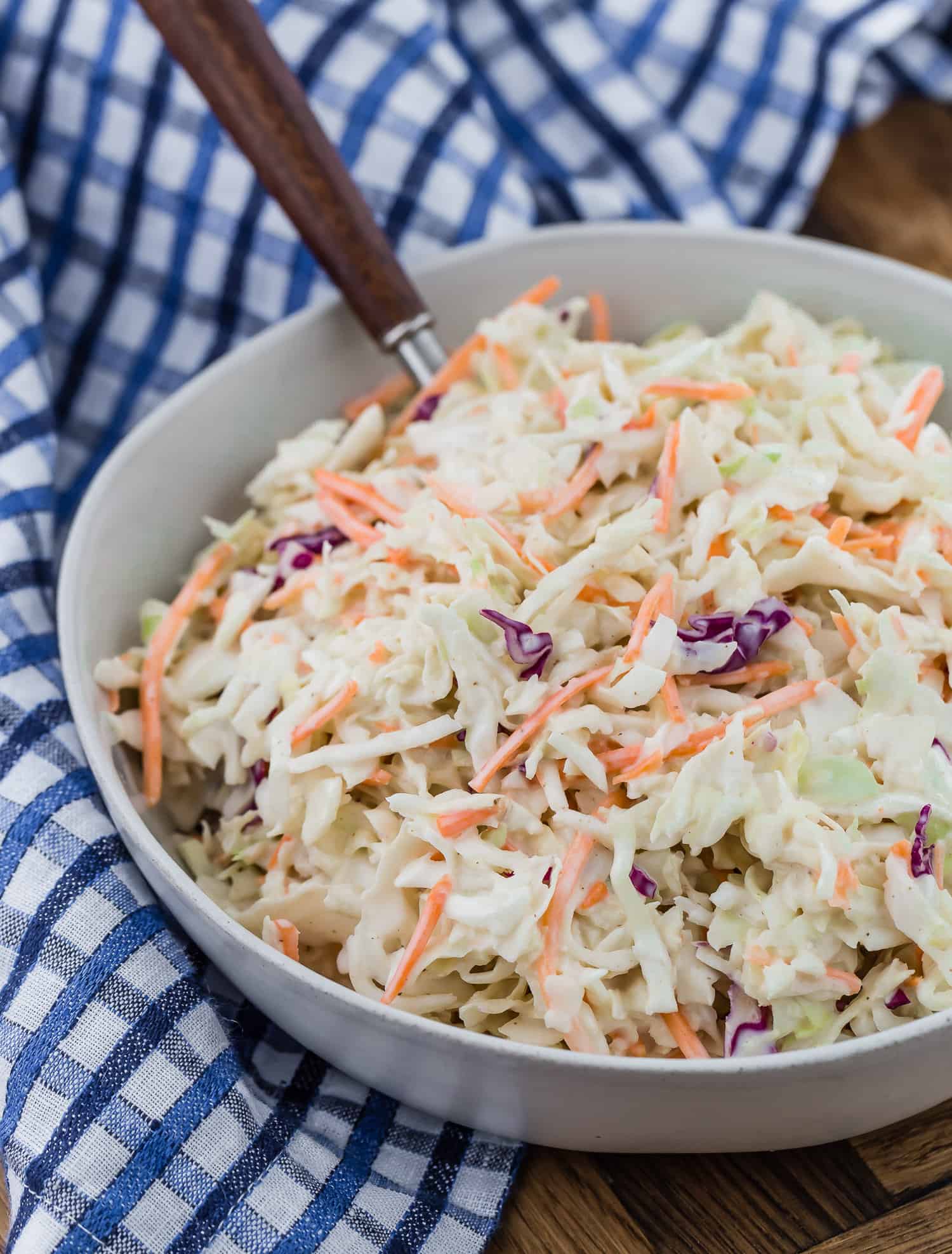 Creamy coleslaw with a wooden handled spoon.