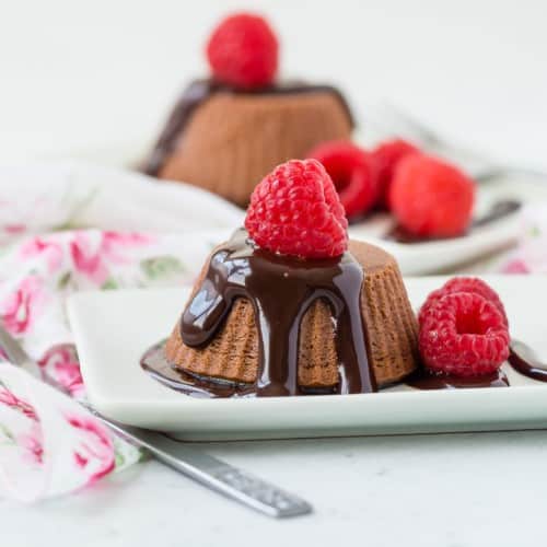 A small chocolate cheese cake on a white plate, with raspberries.