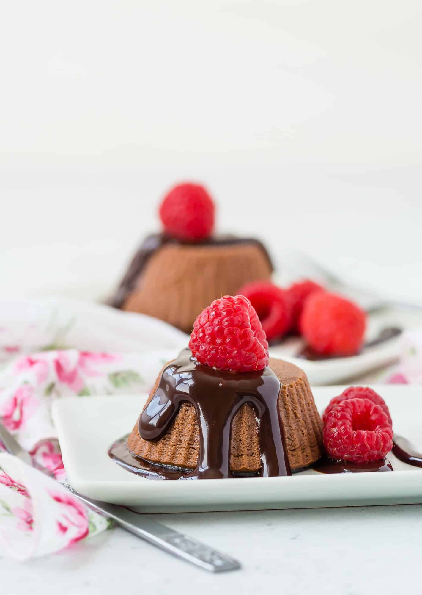 Healthy mini chocolate cheesecakes with chocolate sauce and raspberries.