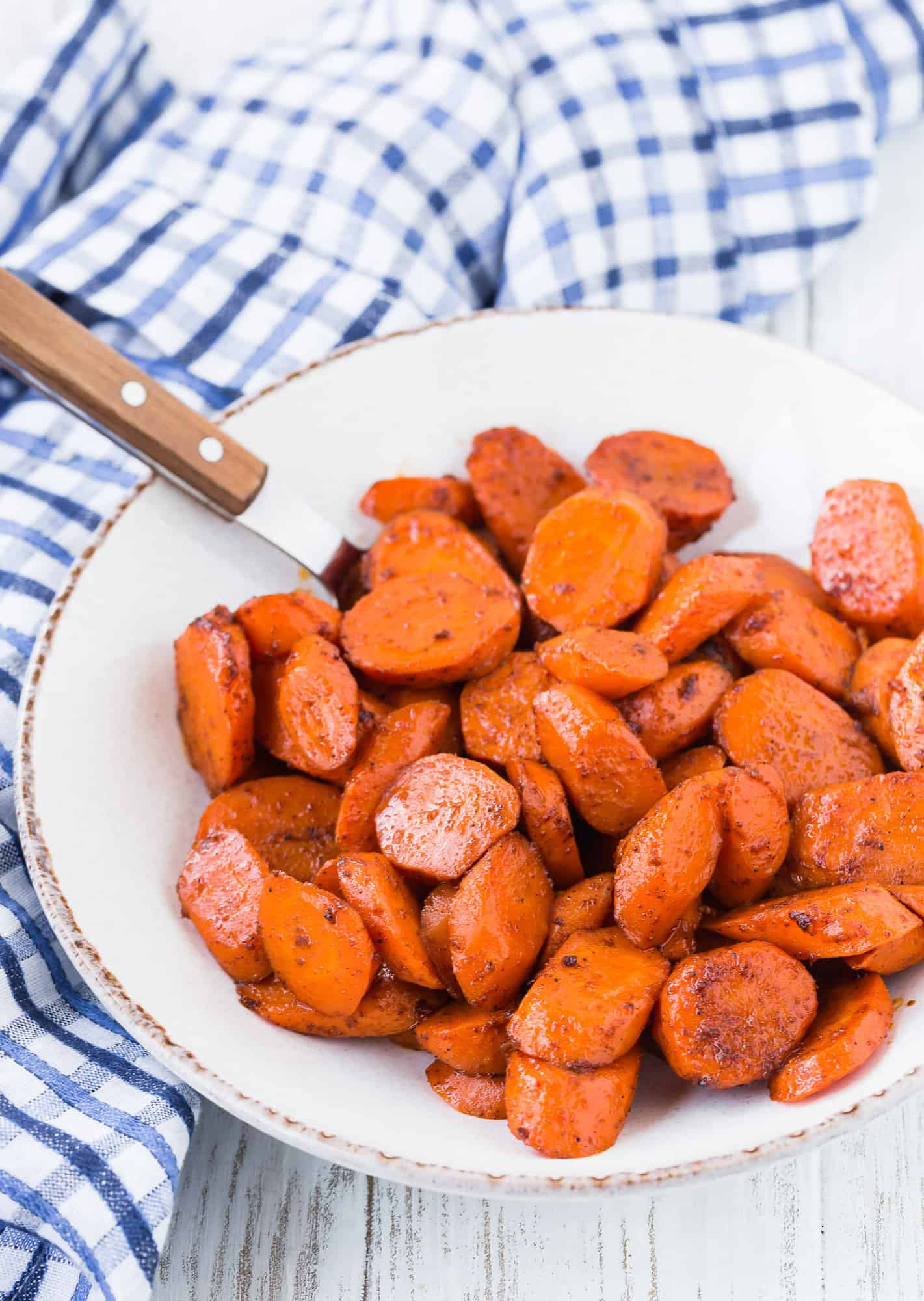 Glazed carrots with honey in a white bowl with a spoon.