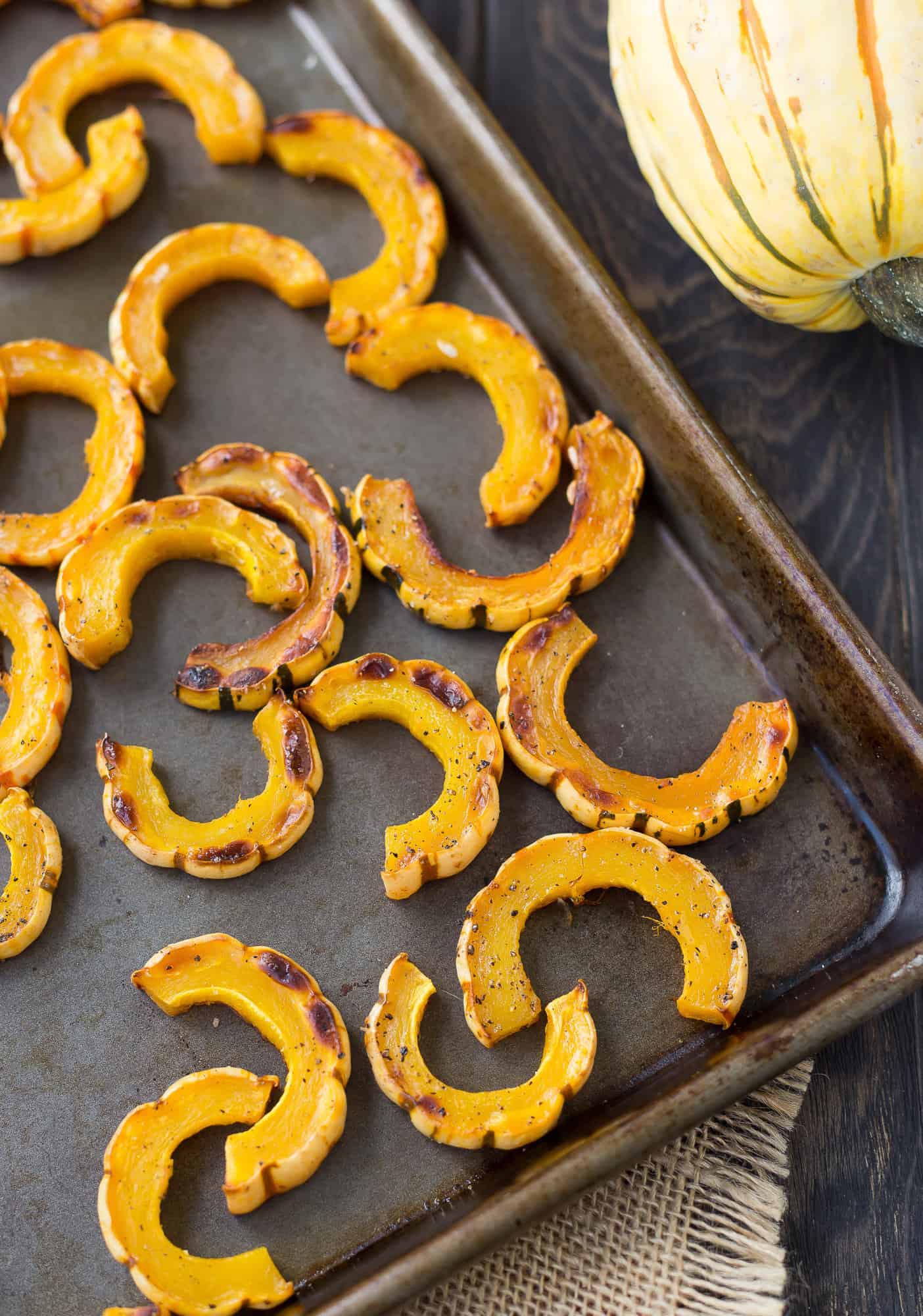 Sliced and roasted delicata squash on a sheet pan.