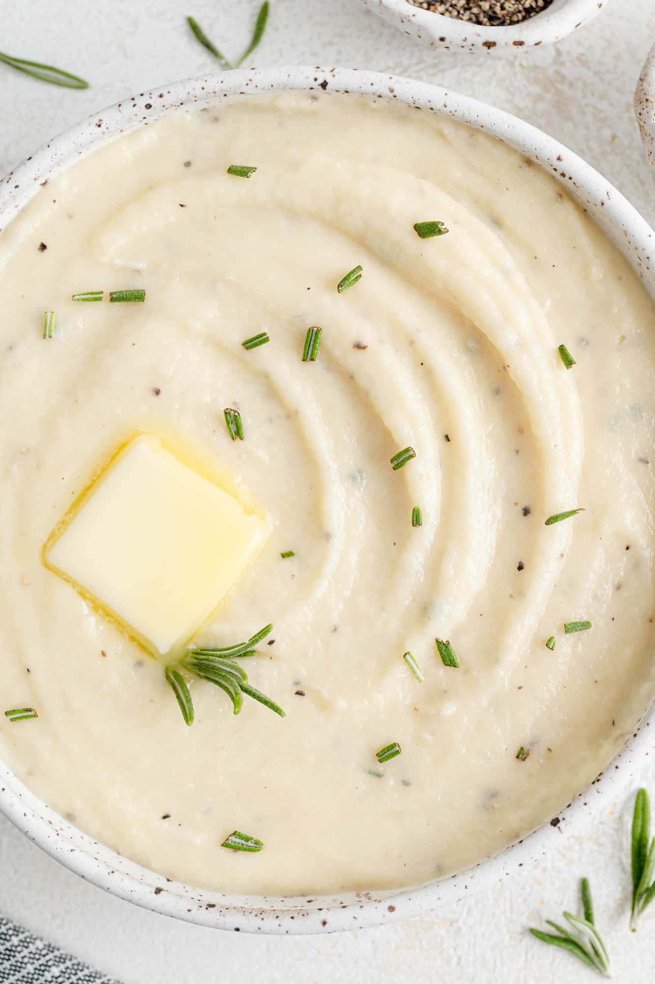 Parsnip puree in a white glass bowl garnished with butter.