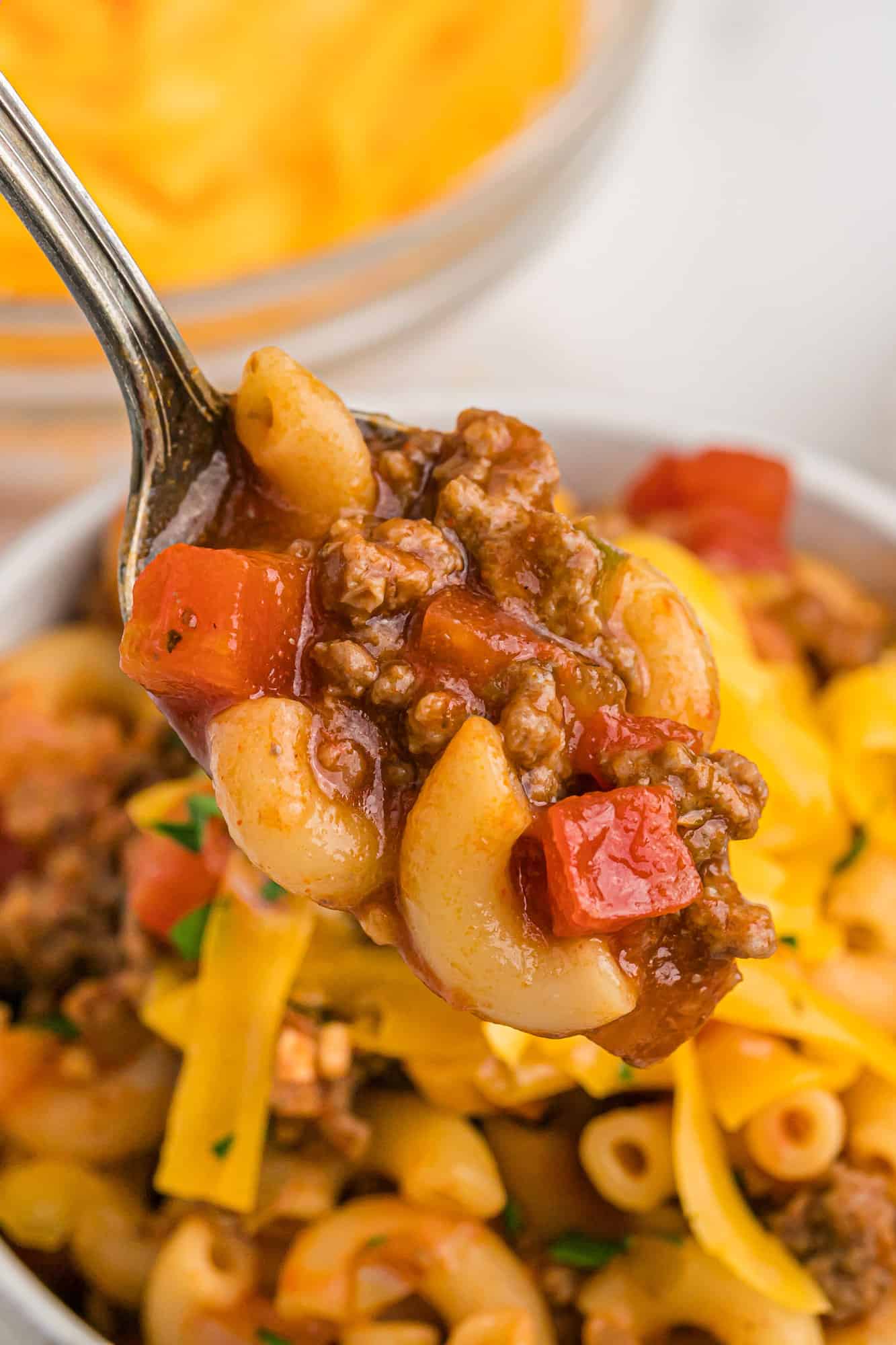 Goulash with cheddar cheese on a spoon.