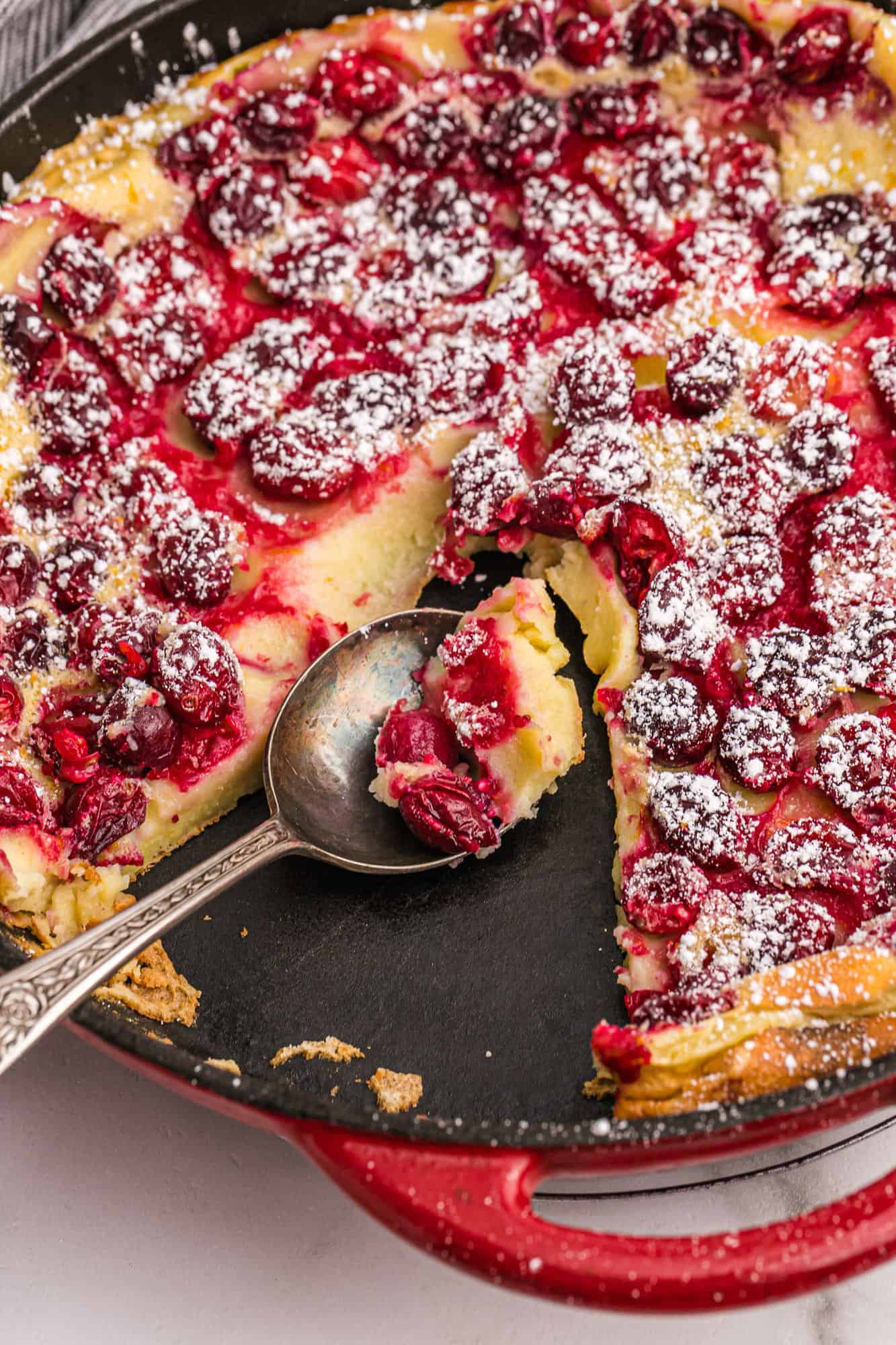 Cranberry clafoutis with a slice removed.