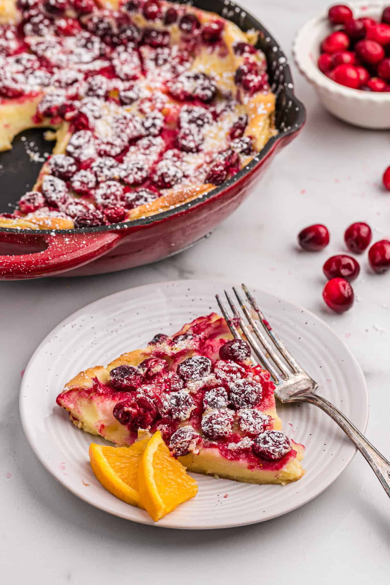 Plated clafoutis with orange wedges.