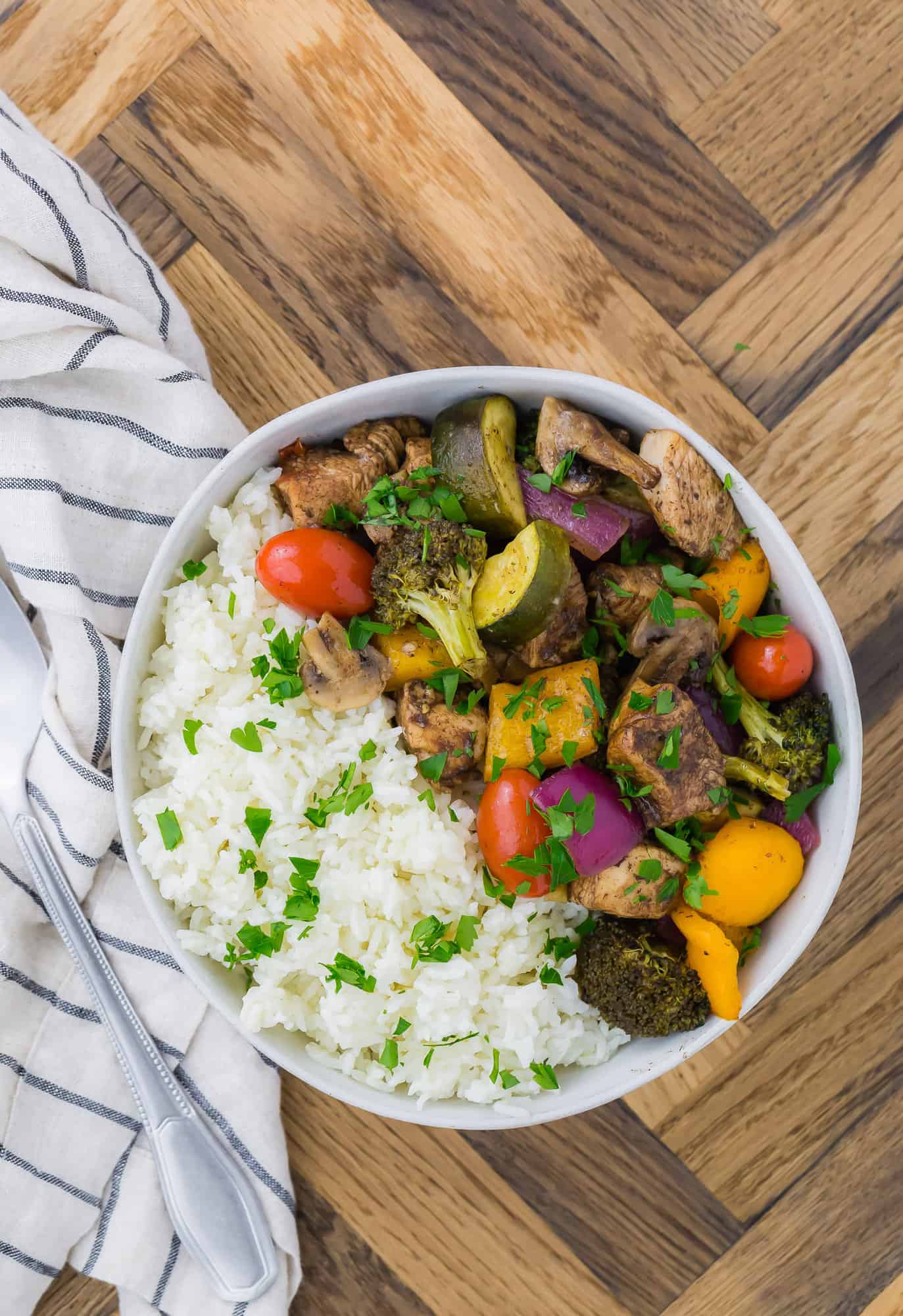 A white bowl filled with rice, chicken and vegetables.