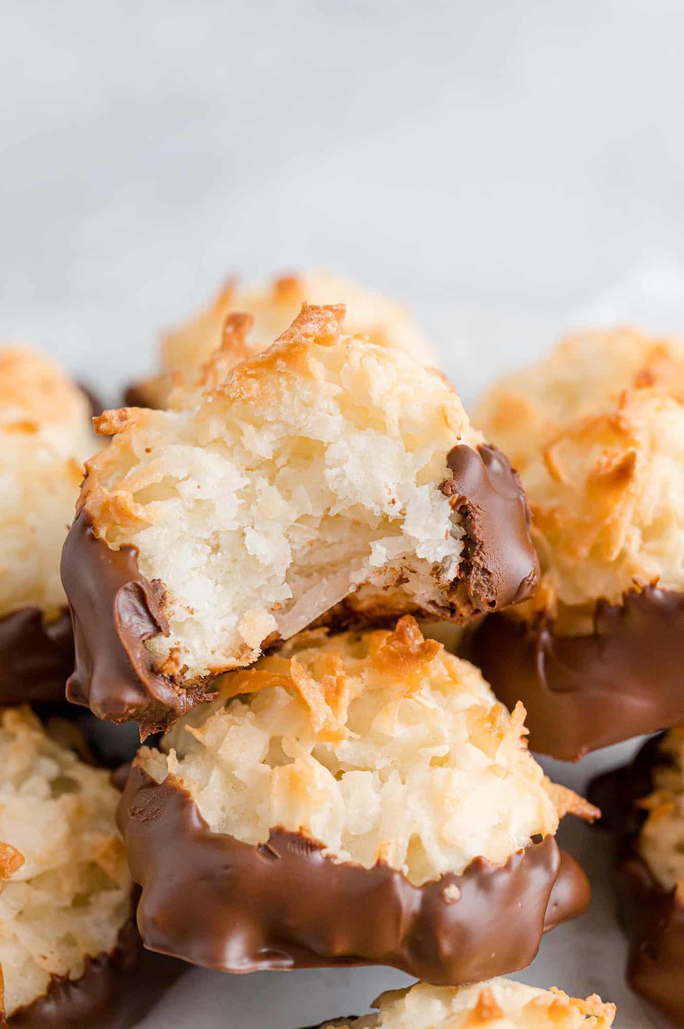 Pile of coconut macaroons, one with bite taken.