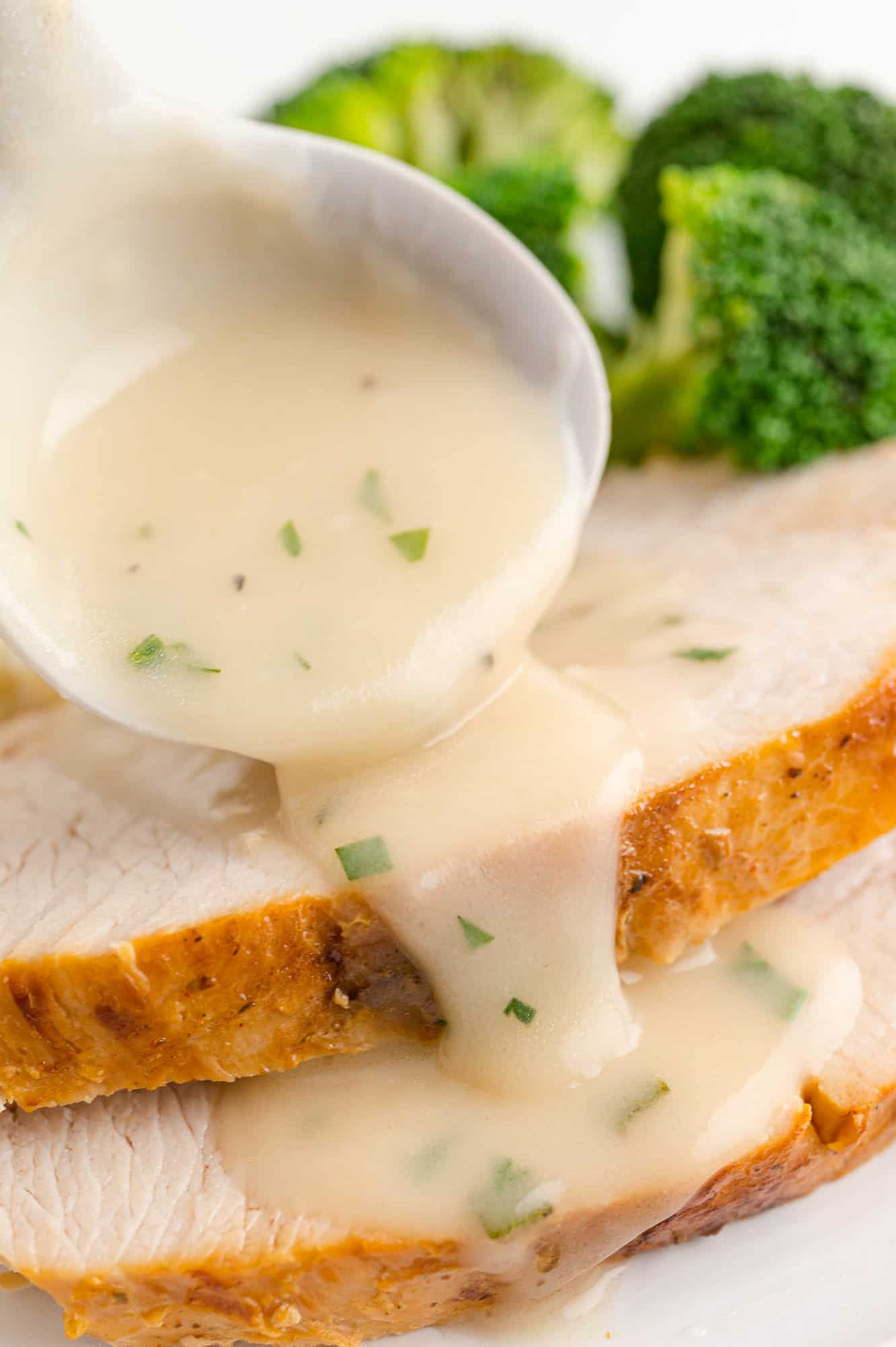 Gravy being poured on turkey slices.