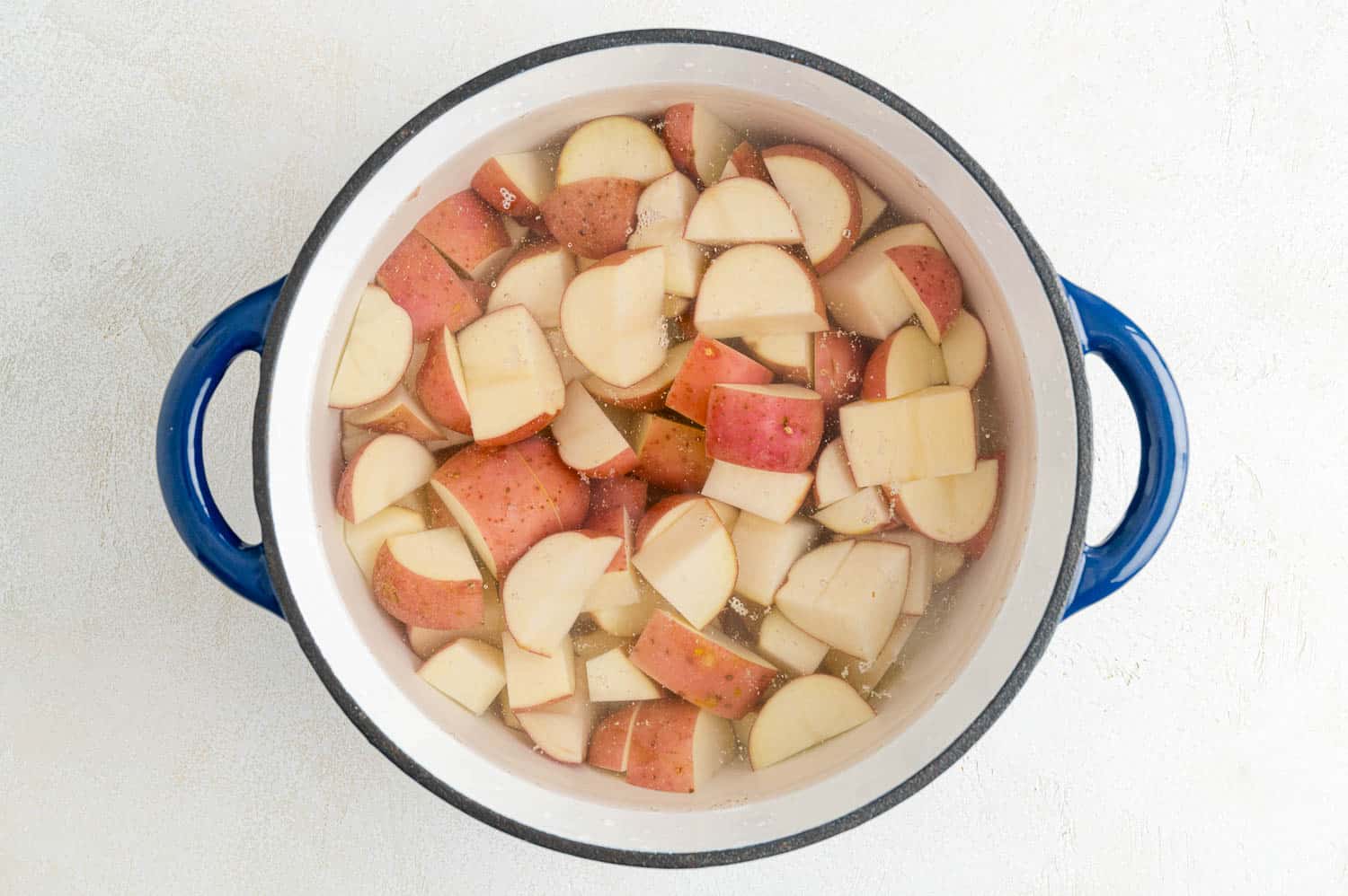 Uncooked potatoes covered by water.