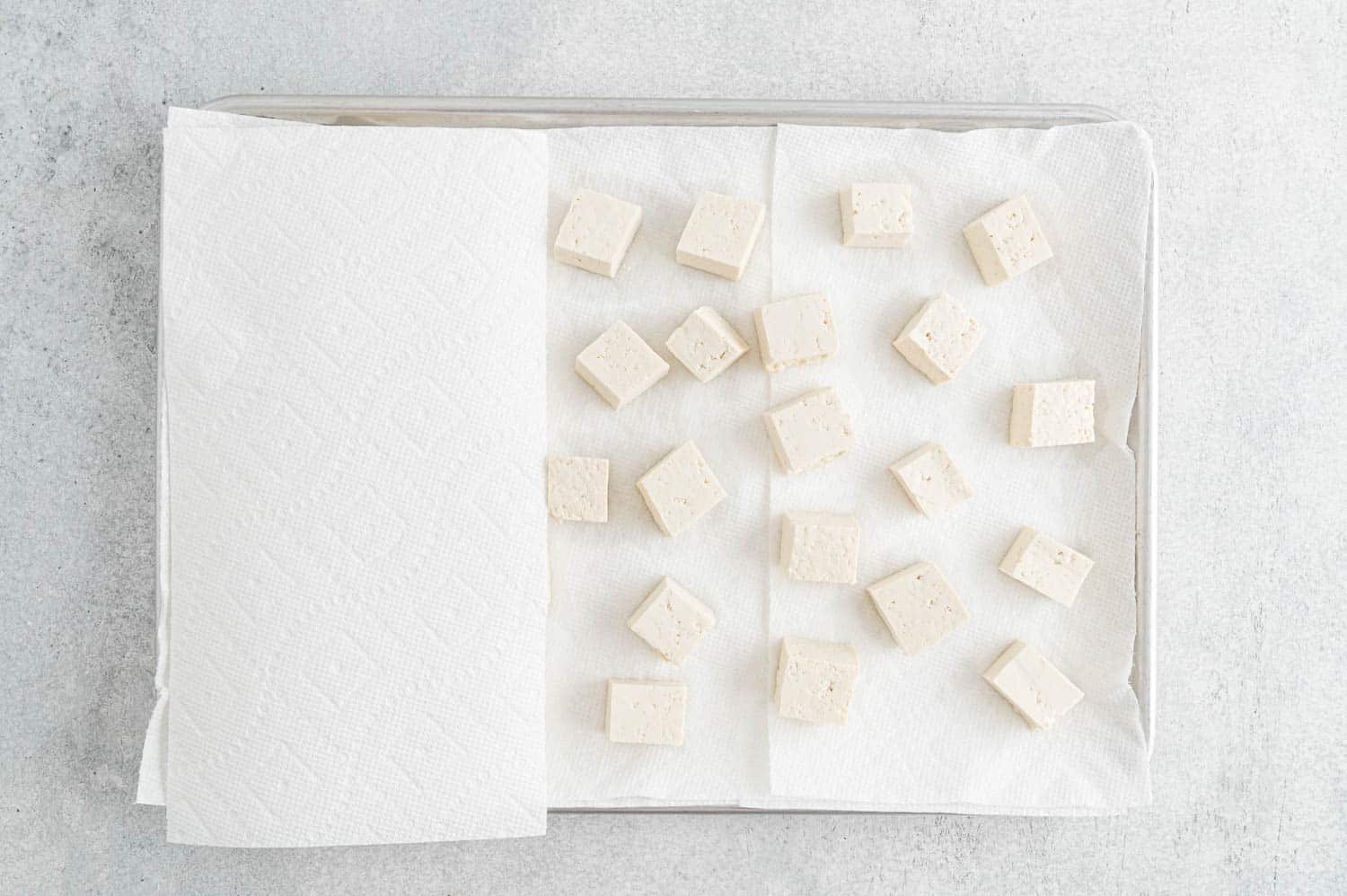 Paper towel being placed on top of tofu.