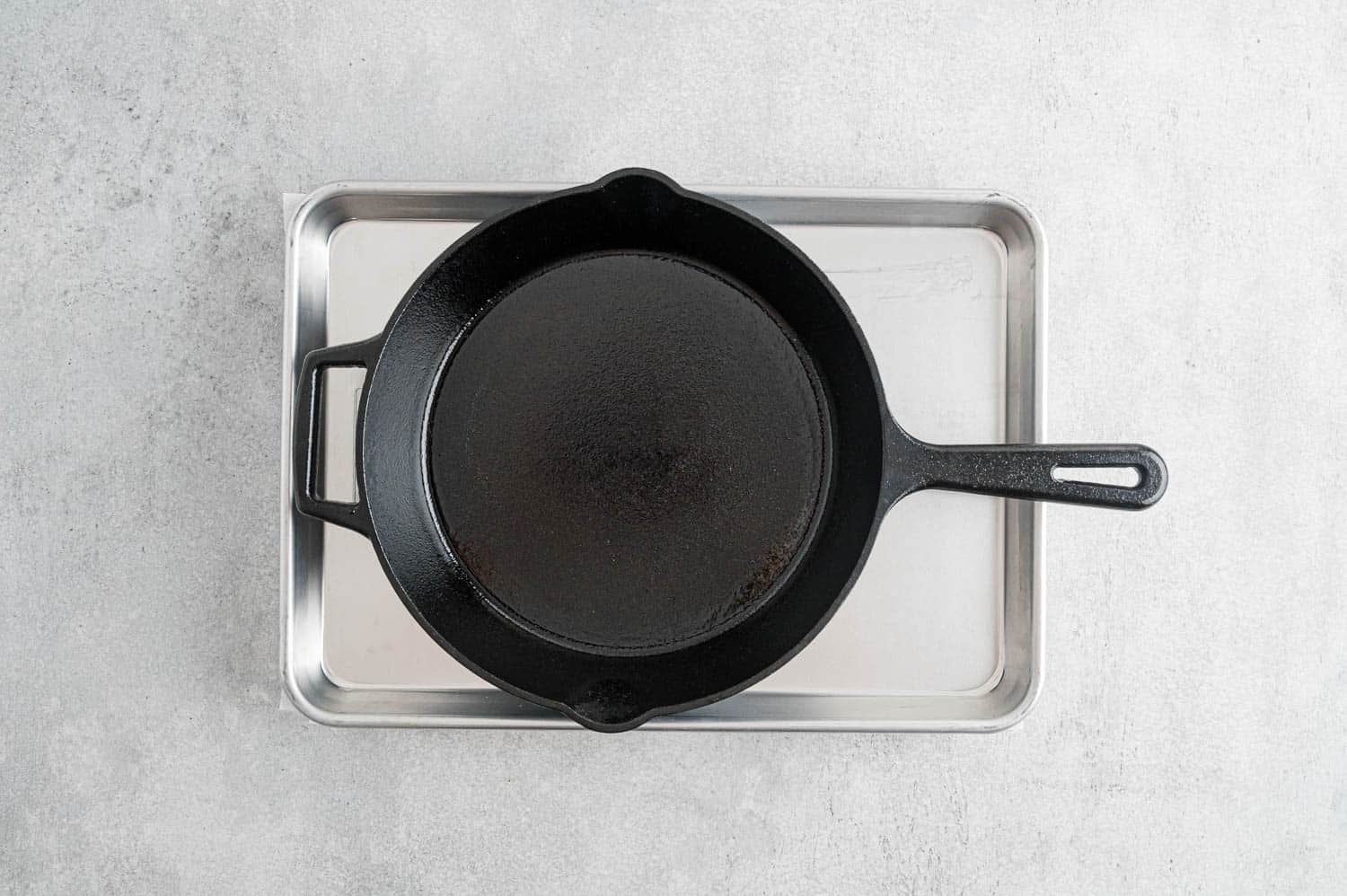 Cast iron pan set on top of baking sheet, pressing tofu.