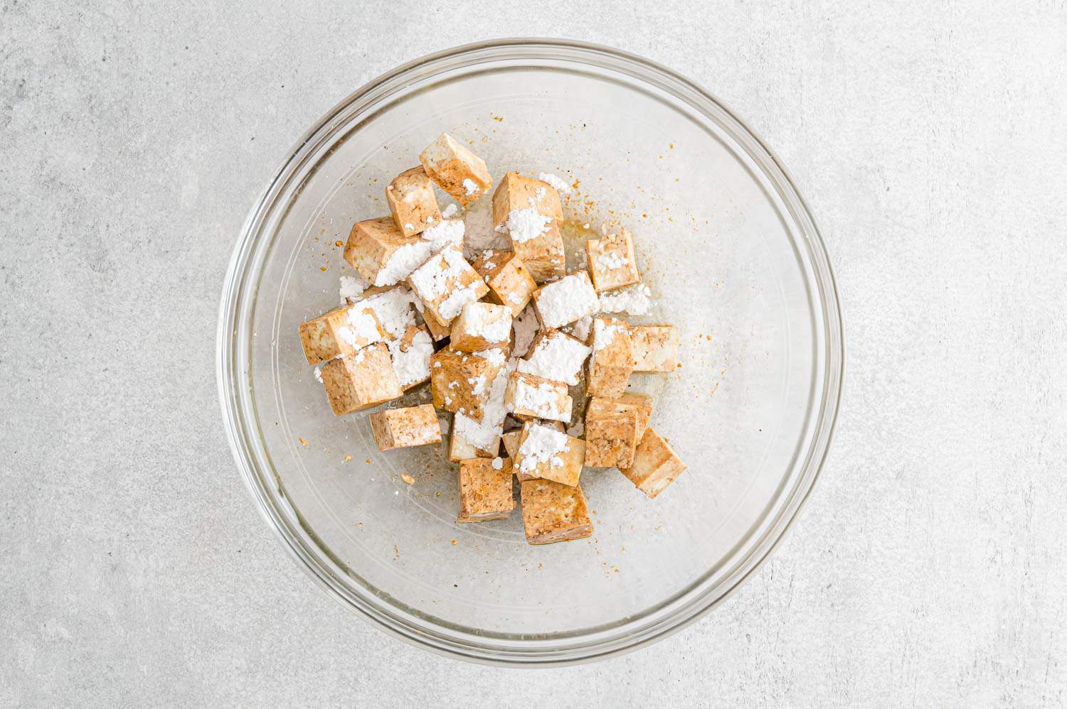 Cornstarch added to seasoned tofu.