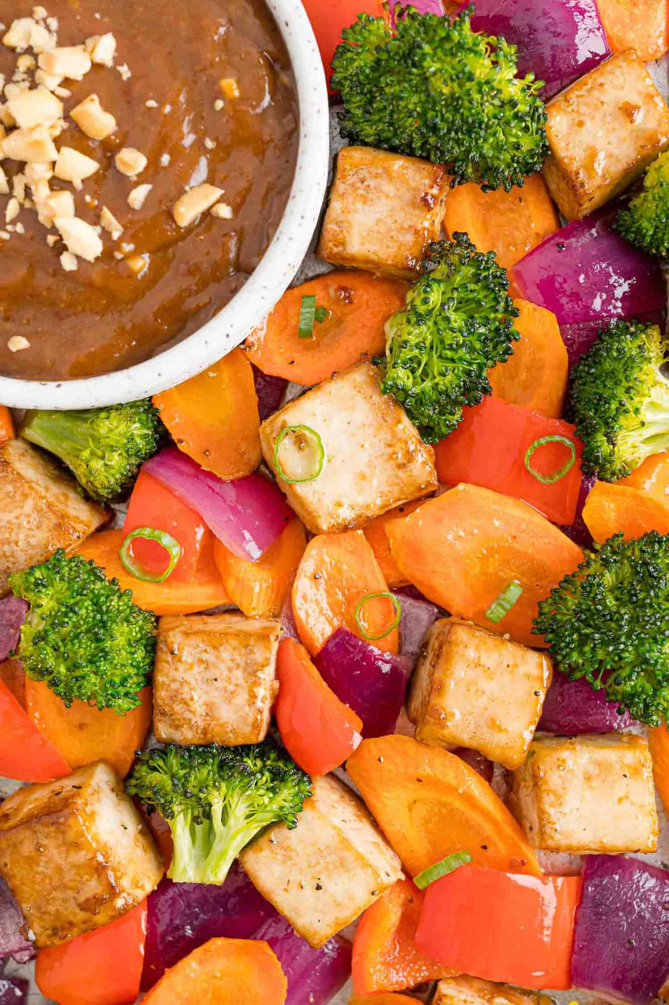 Tofu, vegetables, and sauce on a sheet pan.