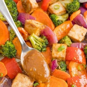 Peanut butter sauce being added to tofu sheet pan dinner.