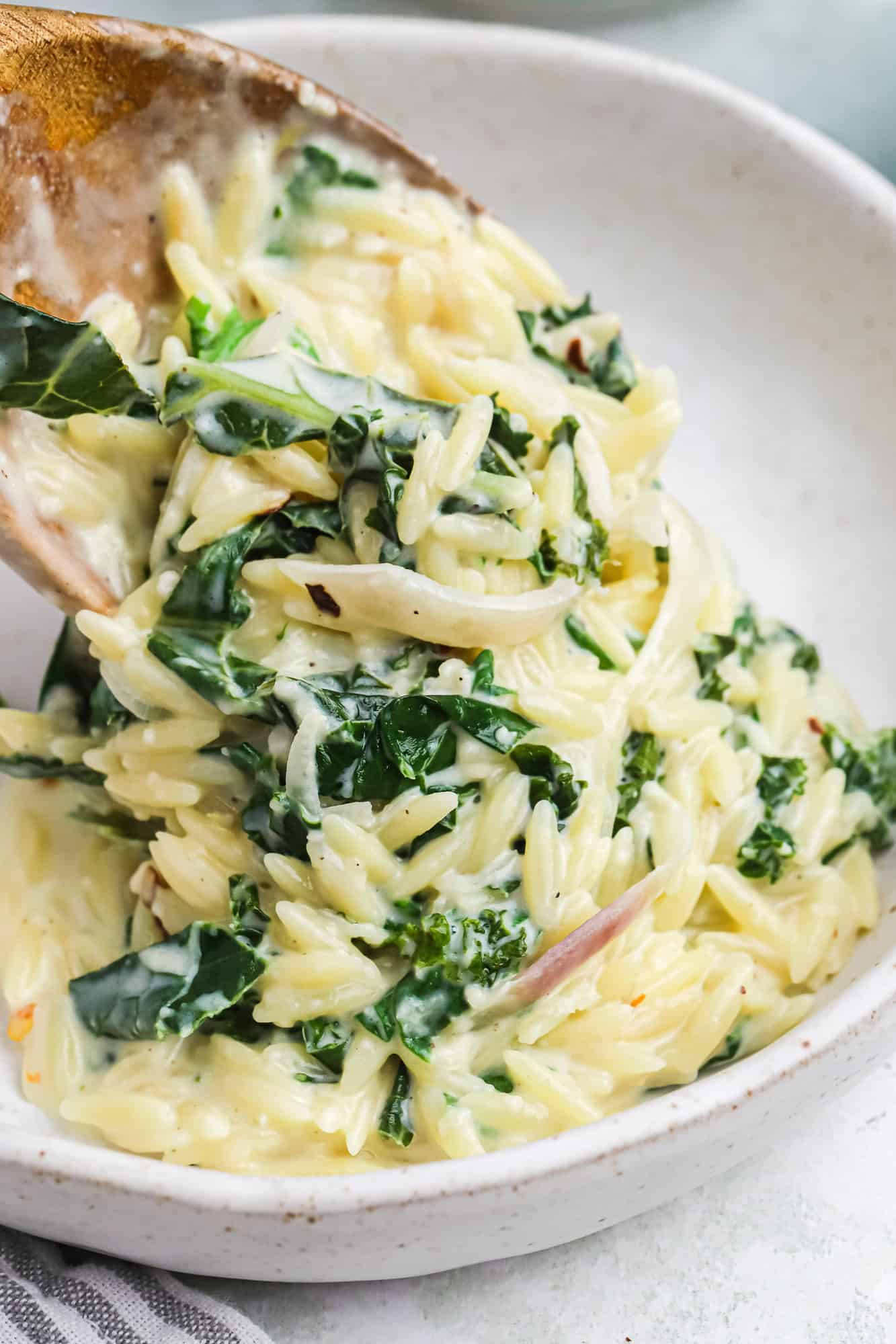 Creamy lemon orzo being scooped into a bowl.