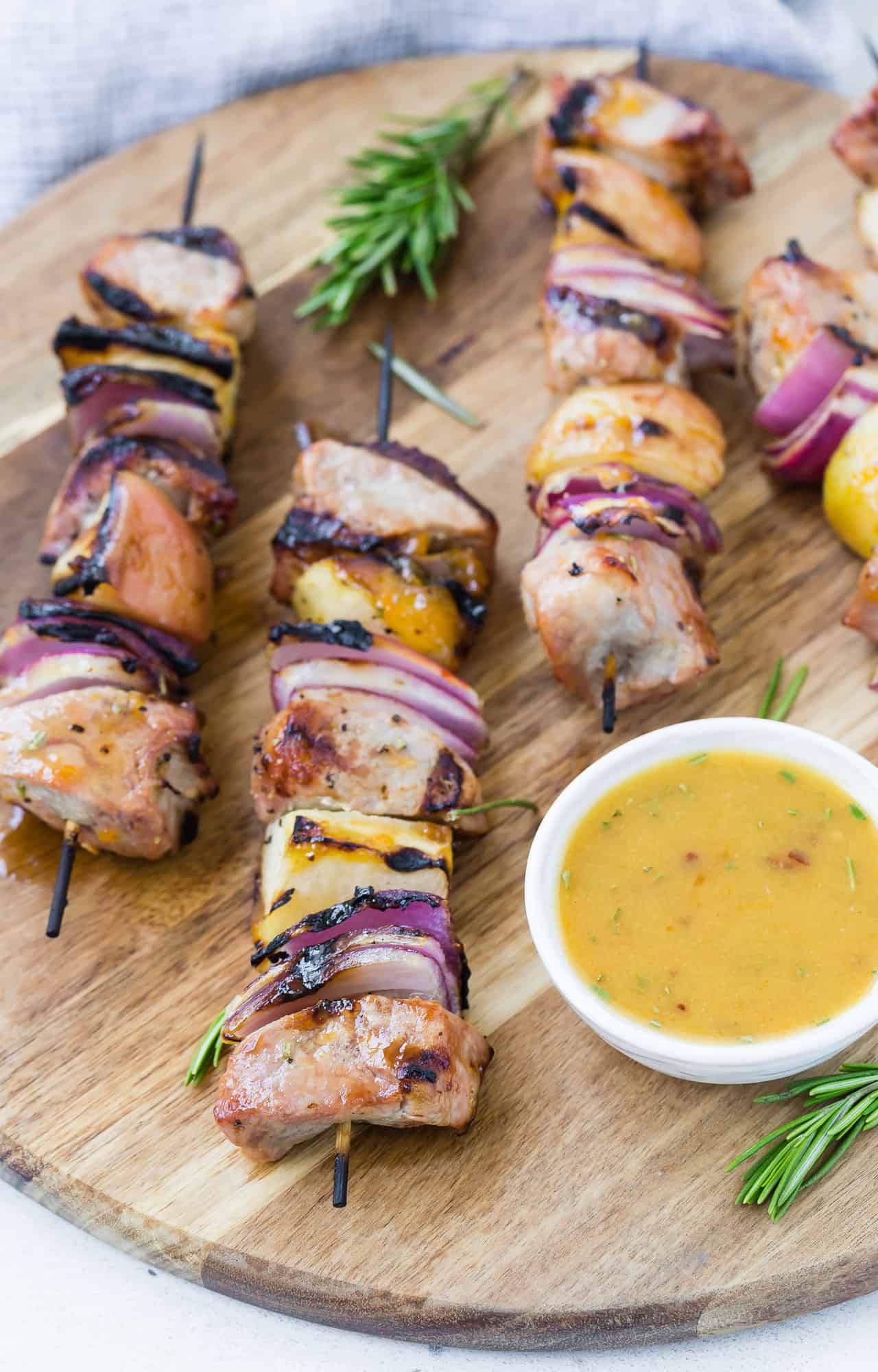 Pork kebobs on a wooden board with sauce.