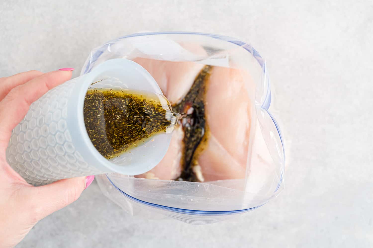 Balsamic marinade being poured on chicken.