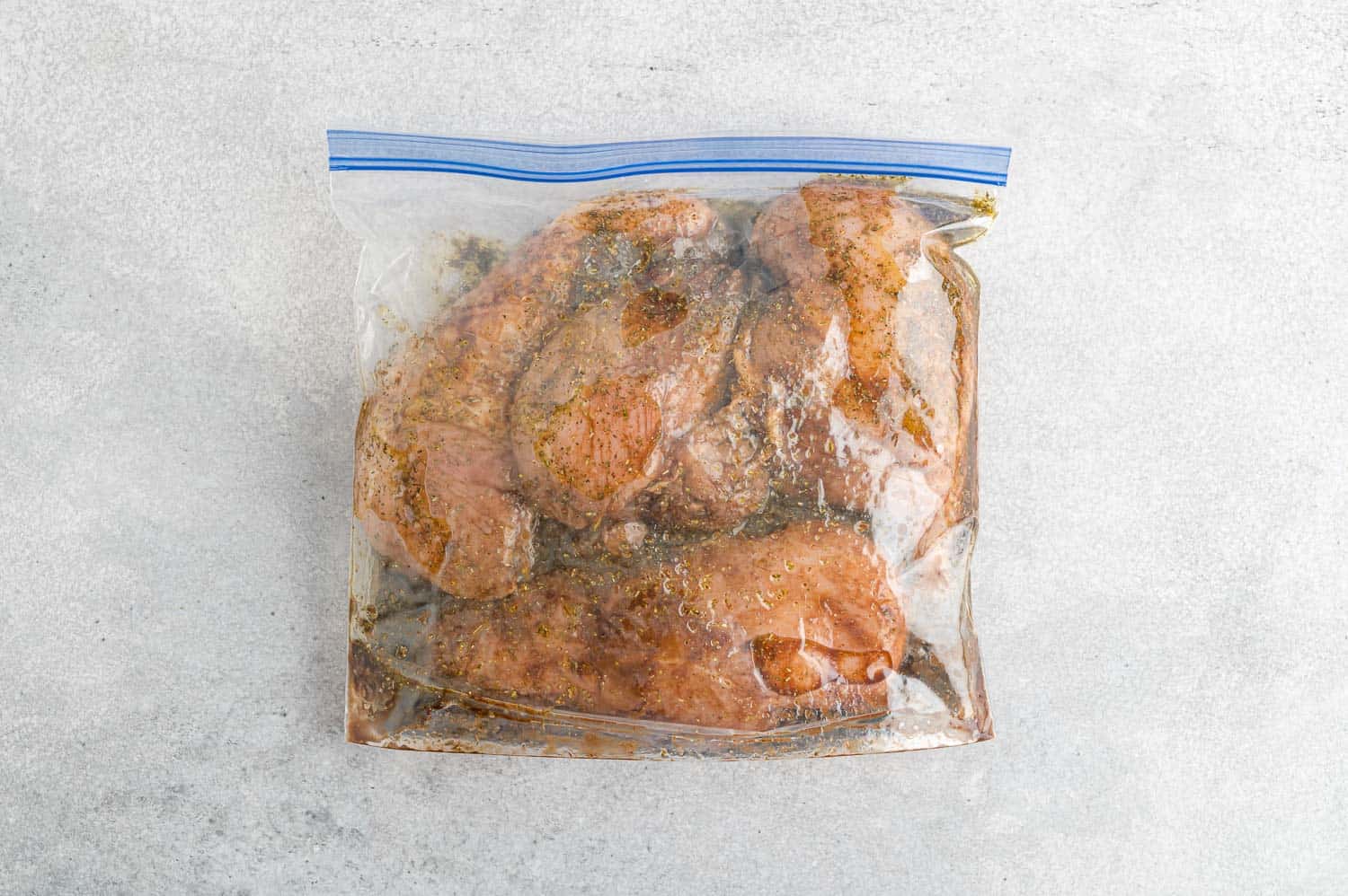 Chicken marinating in a zip-top bag.