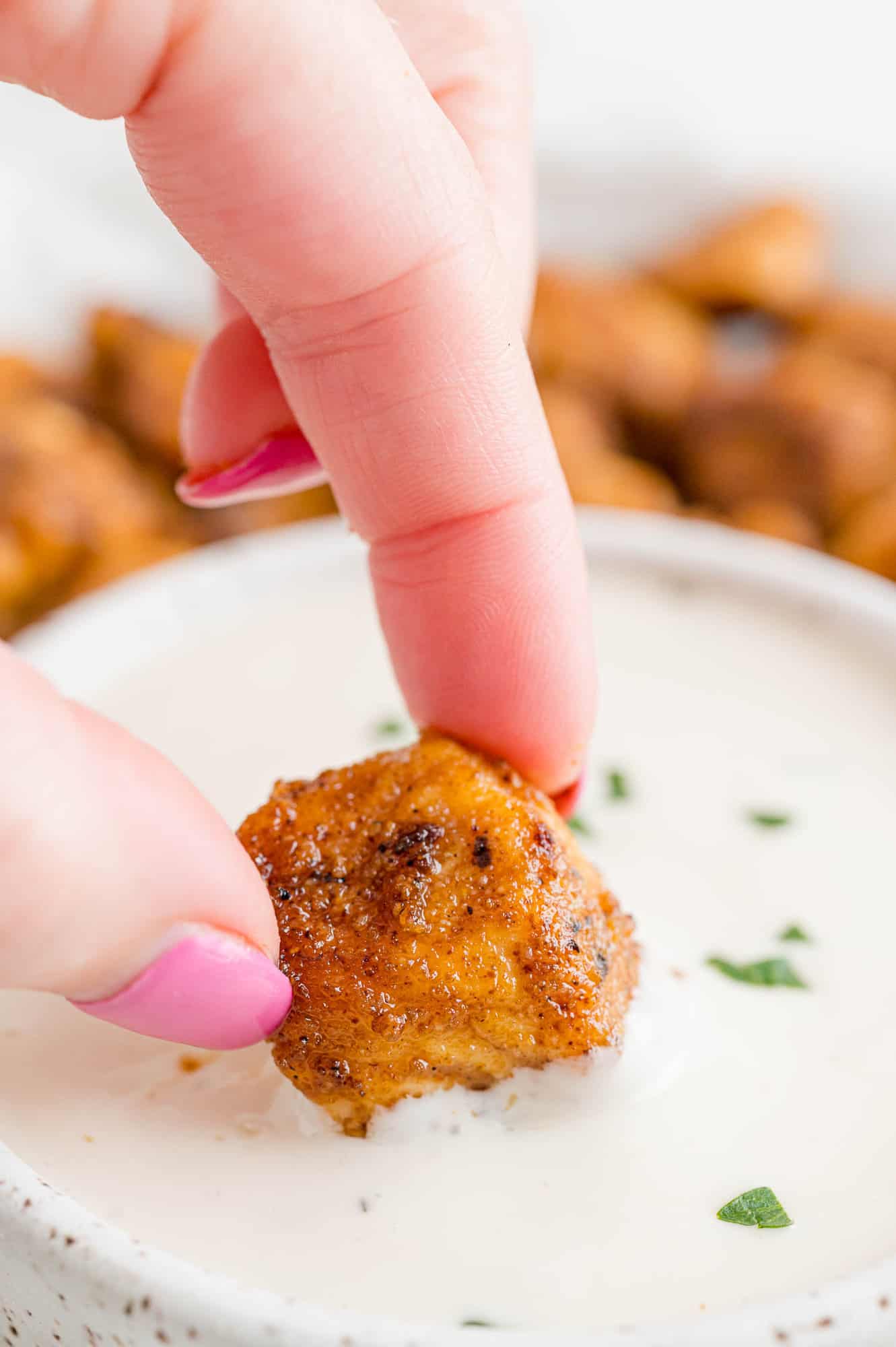 Chicken bite being dipped in ranch dressing.