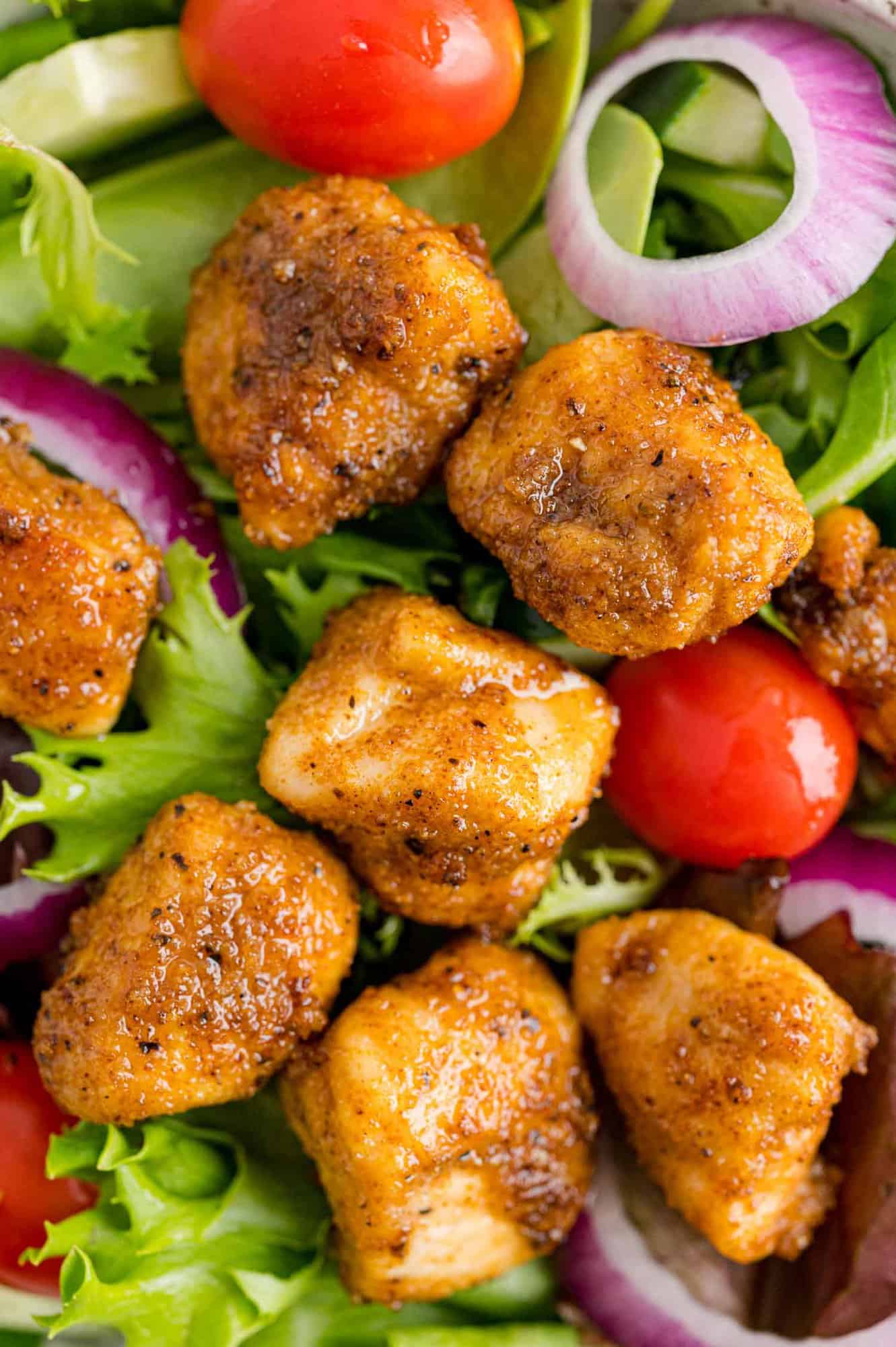 Chicken bites on a tossed green salad.
