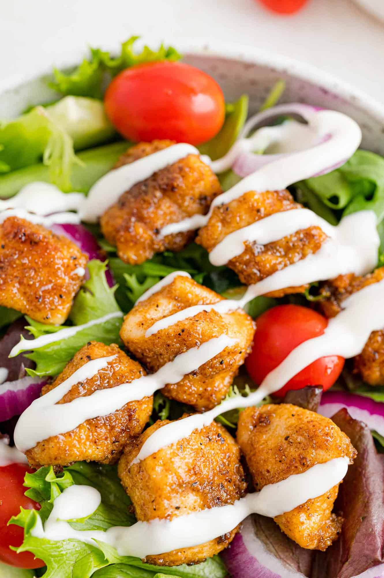 Chicken bites on a salad with ranch dressing.