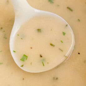 Make ahead turkey gravy in a white ladle.