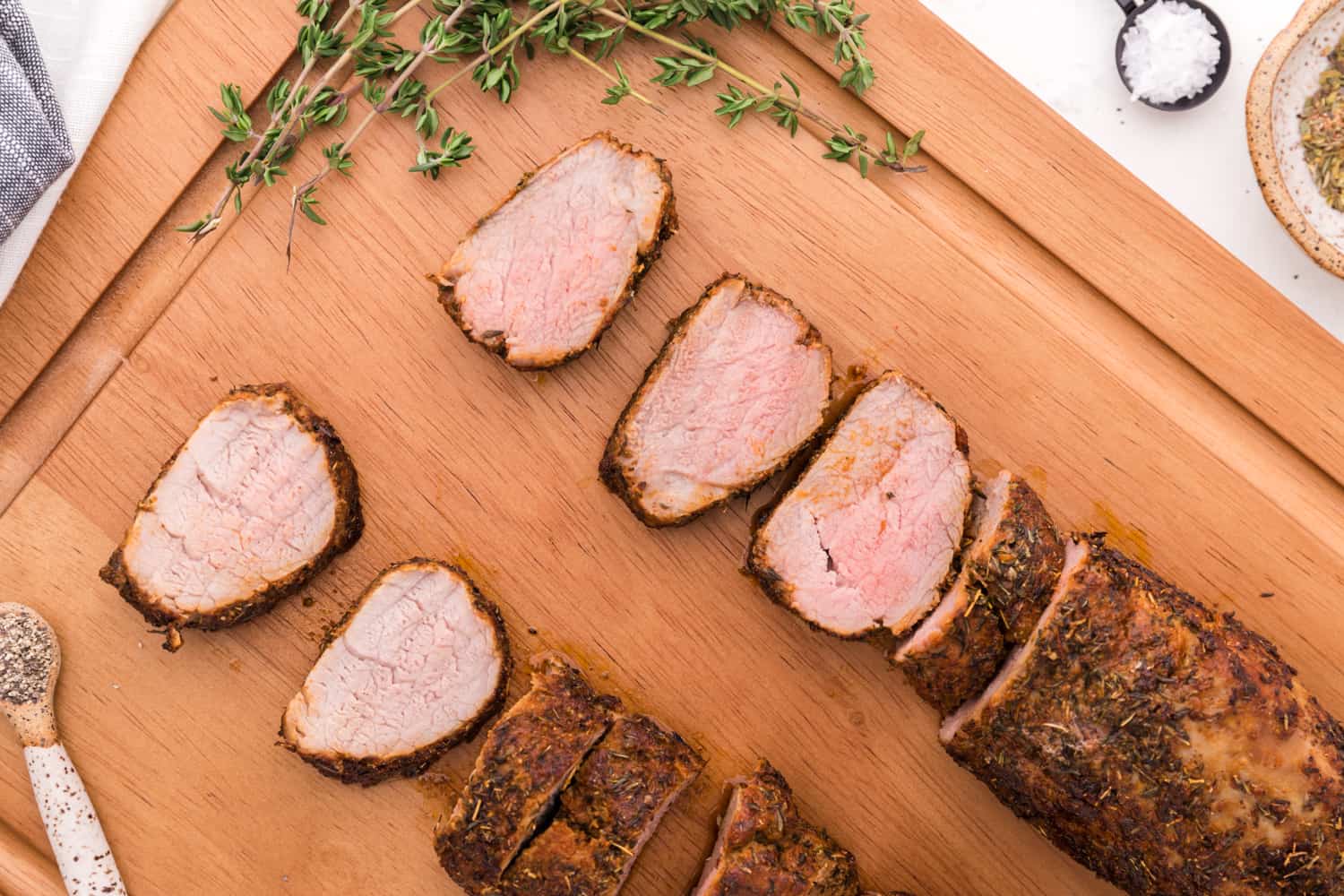 Partially sliced pork tenderloins on cutting board.