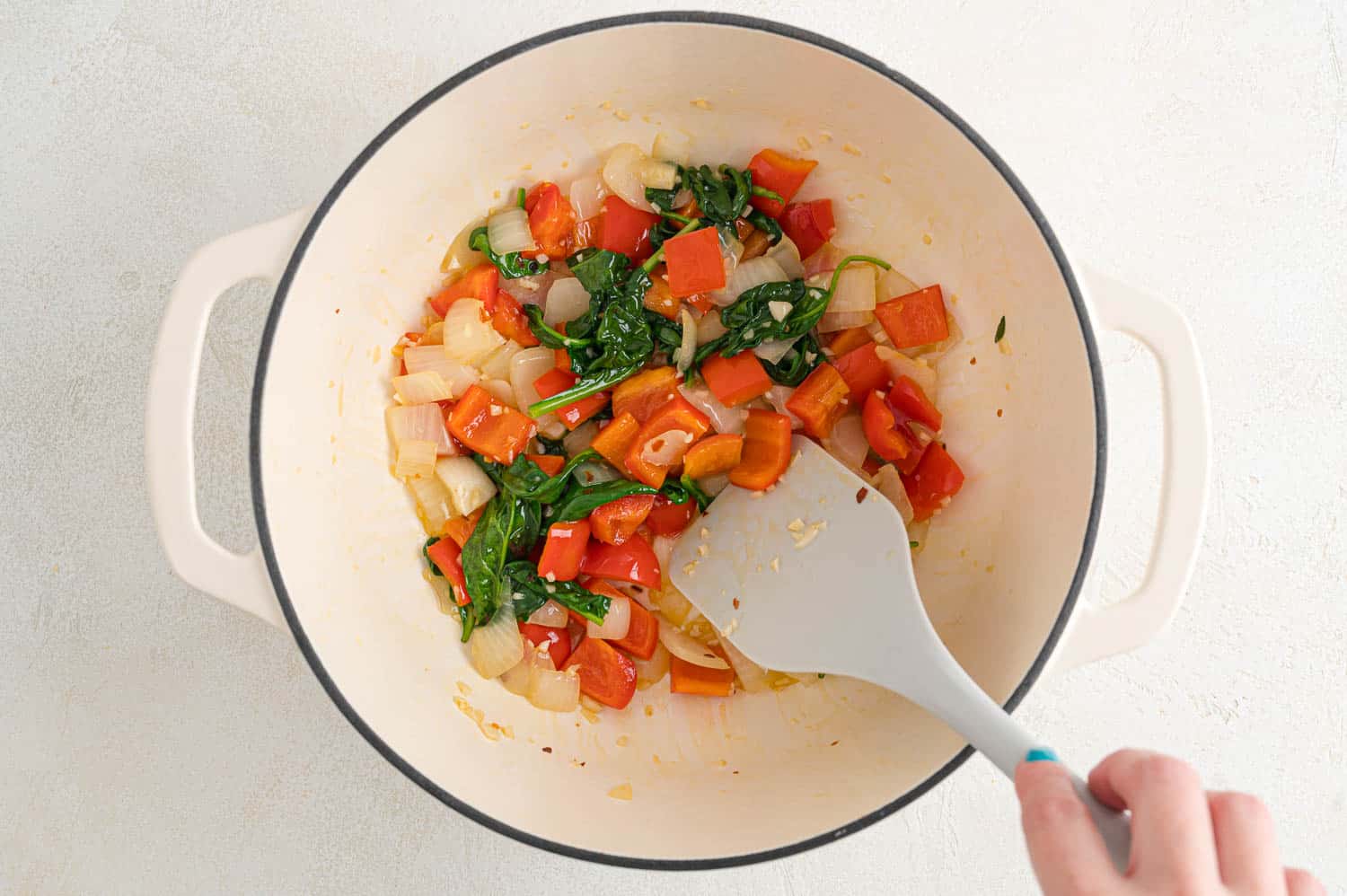 Spinach wilted in pan with peppers and onions.