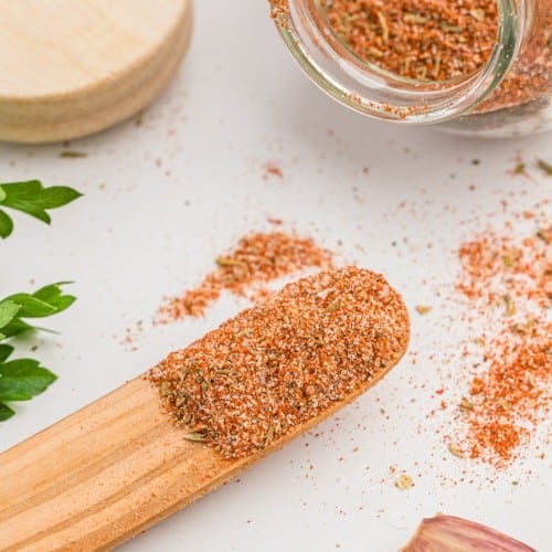 Cajun seasoning on a small wooden spoon and in a jar.