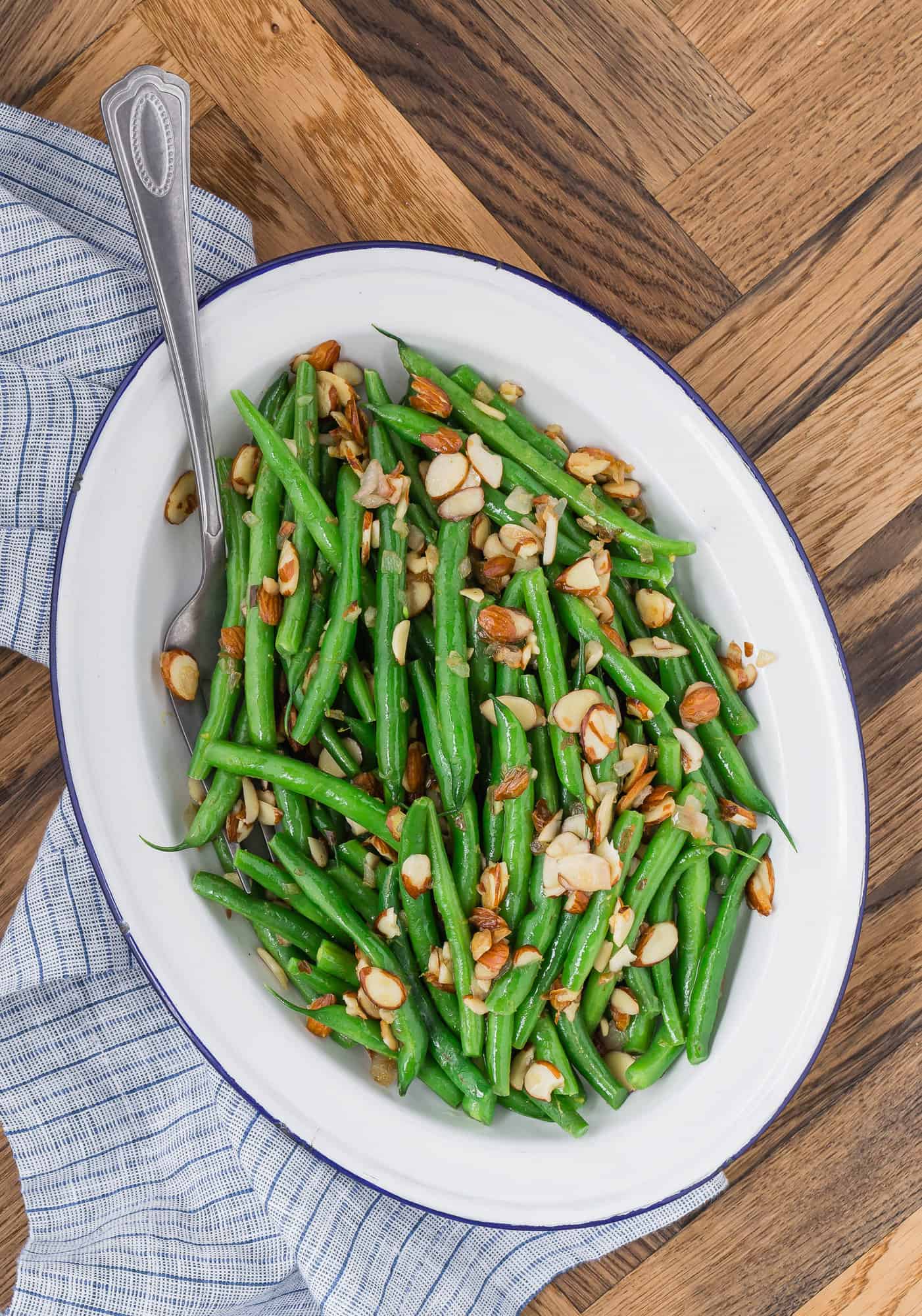 Green beans and almonds on a white platter.