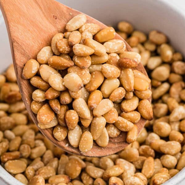 Toasted pine nuts on a wooden spoon.